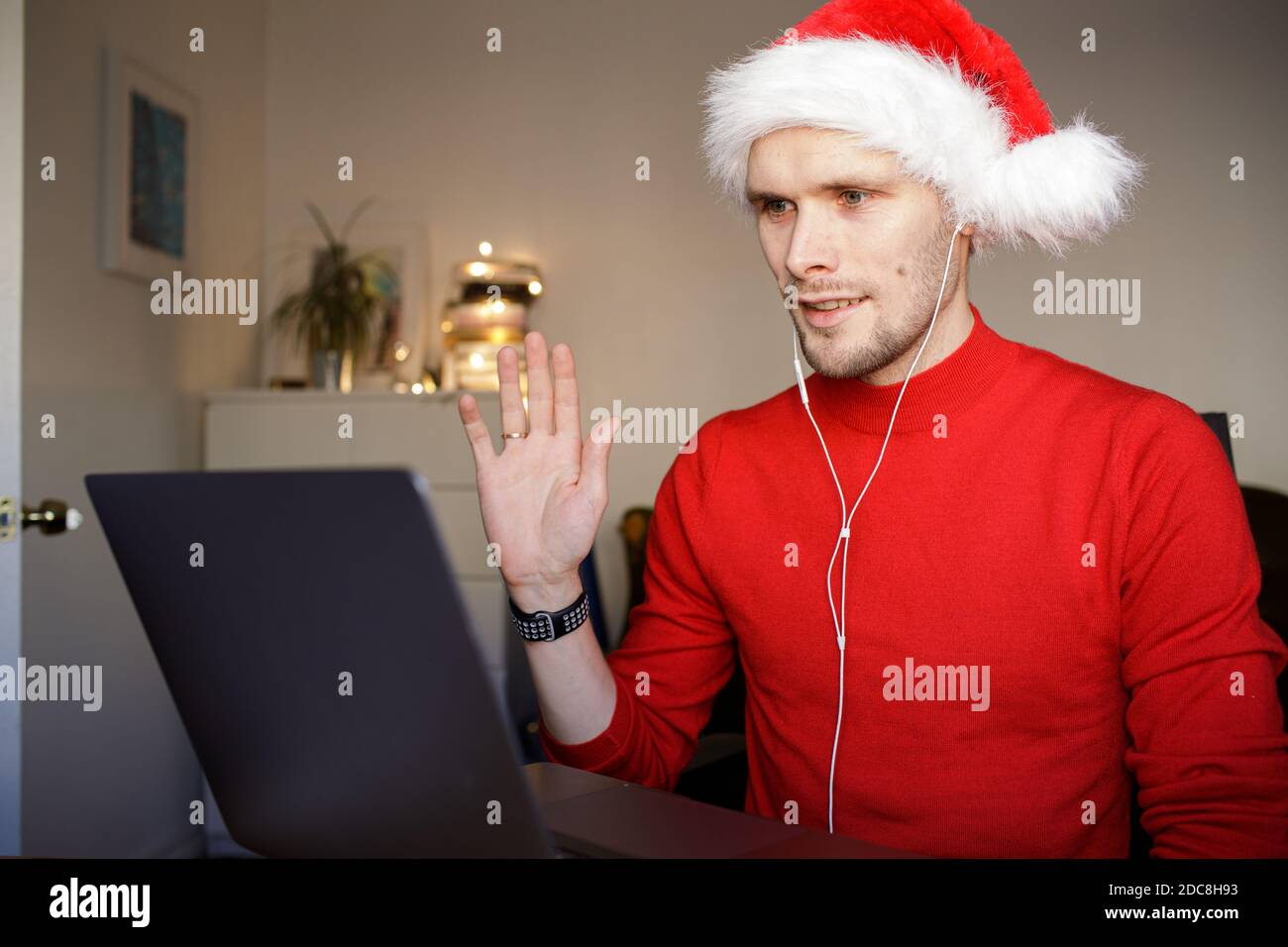 A video call on Christmas computer in the home office. Man wearing Santa hat. Business video conferencing. Virtual thanksgiving house party. Online Stock Photo