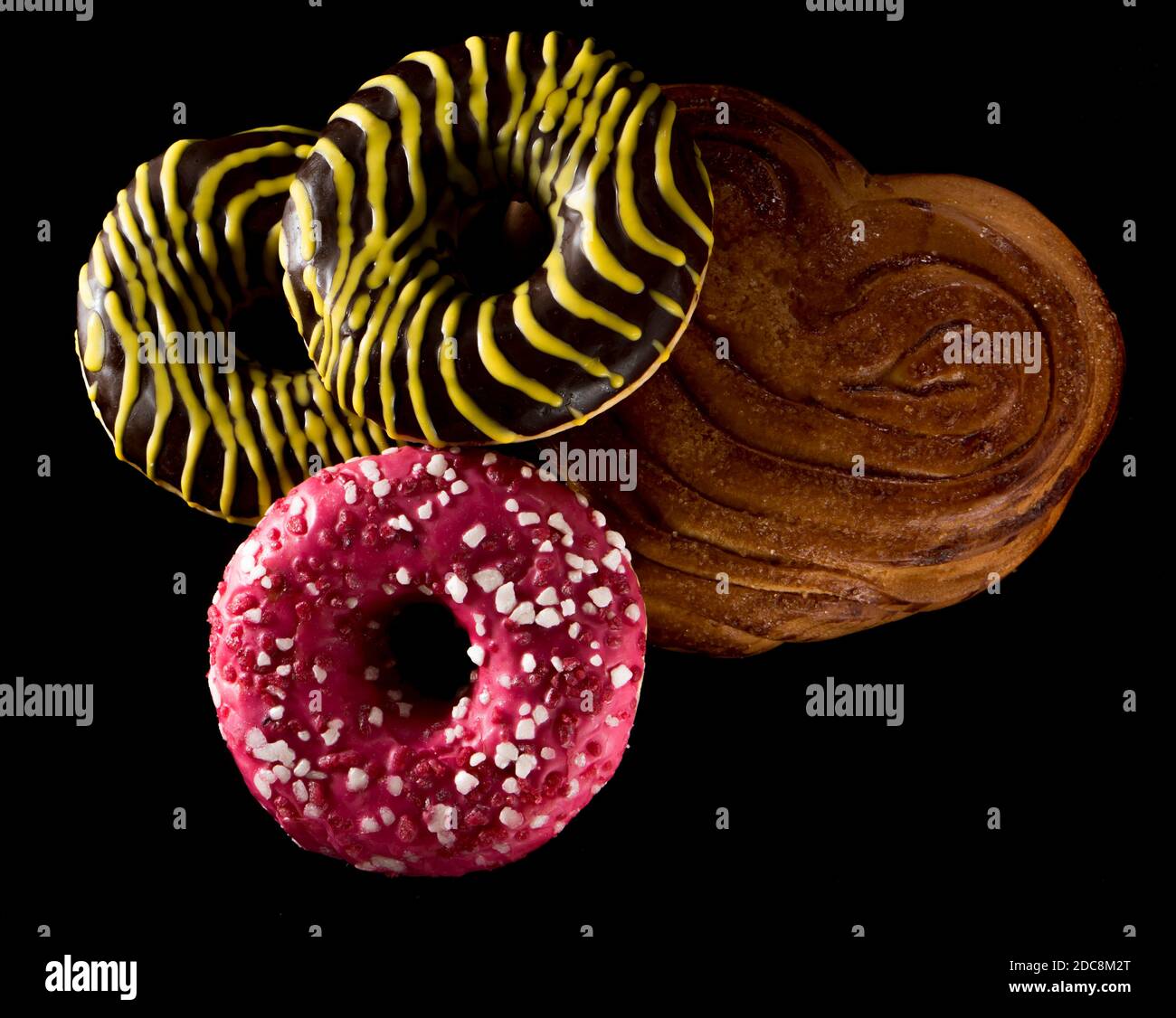 American brown and pink donuts and baked bun on black background Stock Photo