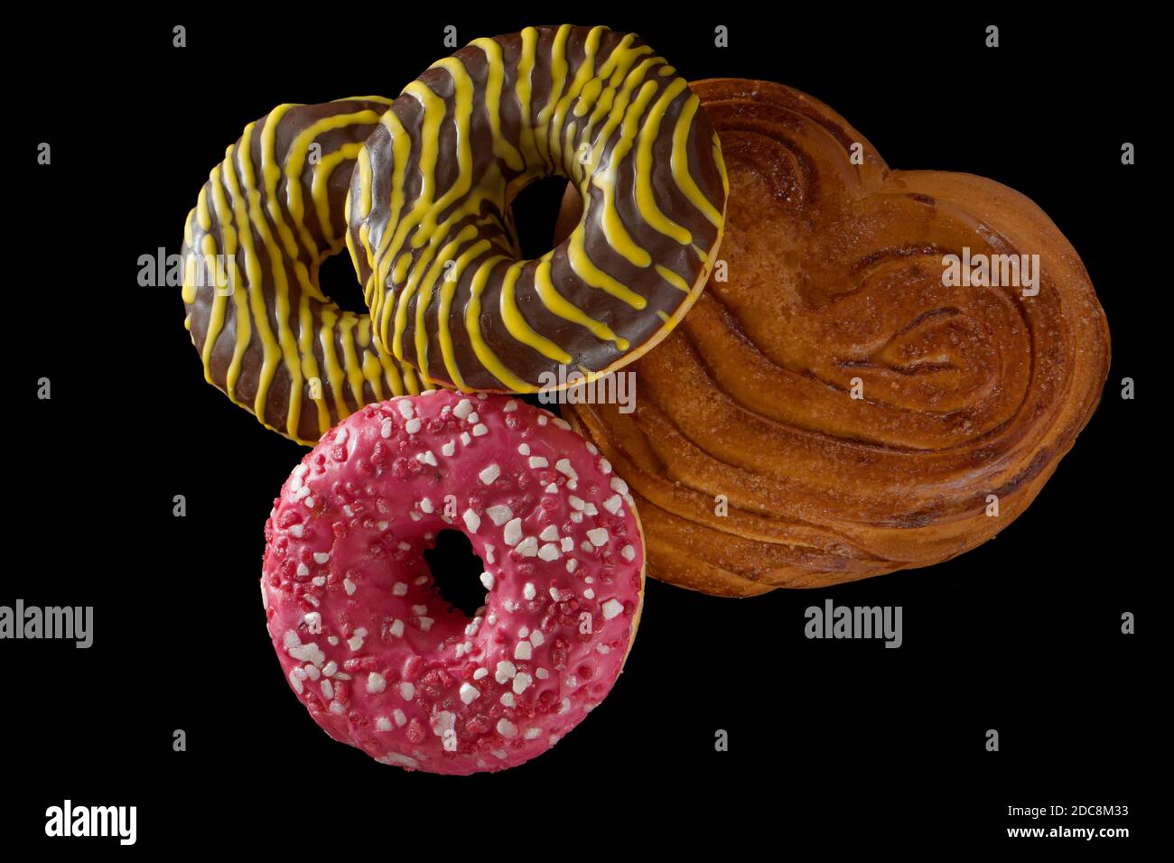 American brown and pink donuts and baked bun on black background Stock Photo