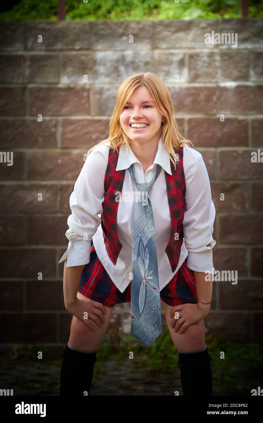 Young girl with short hair in a school checkered uniform outdoors Stock Photo