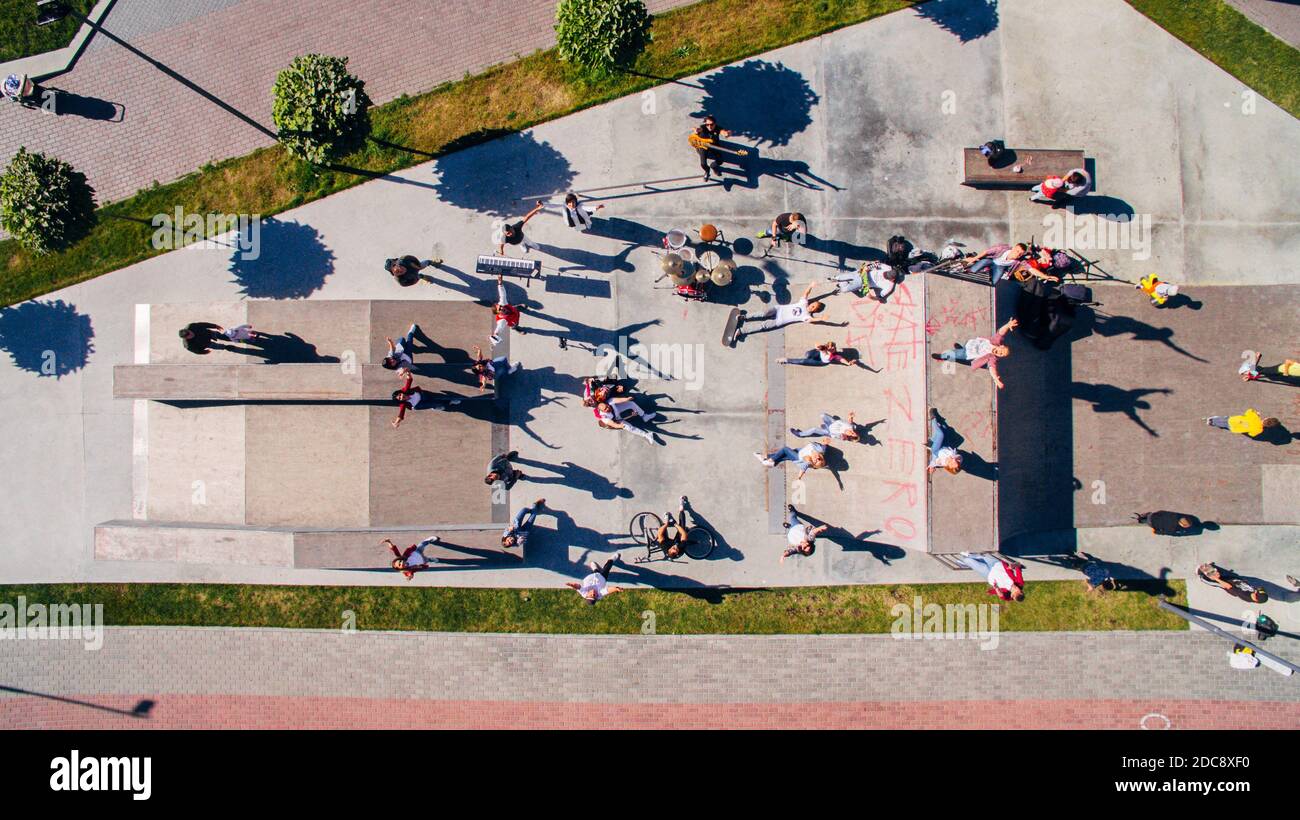 Aerial view of happy youth with musical instruments in a skate park on the embankment. Surreal storyline. Stock Photo