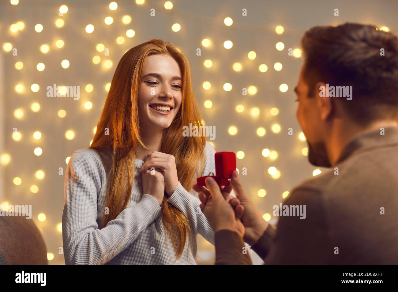 Excited young woman getting and accepting a marriage proposal from her boyfriend Stock Photo