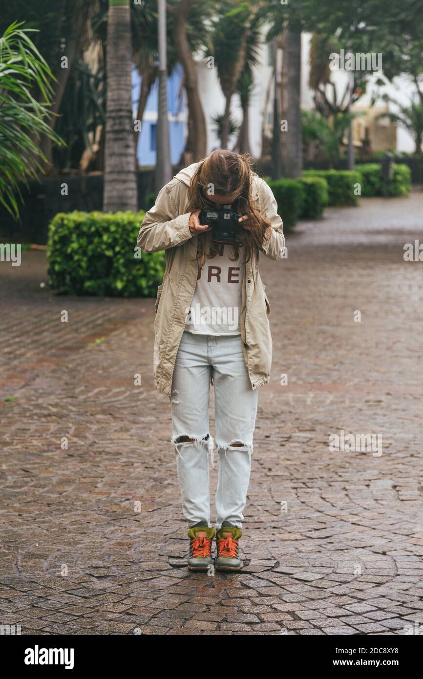 Young hipster woman holding reflex camera and taking photos of her boots on  wet stone pavement Stock Photo - Alamy