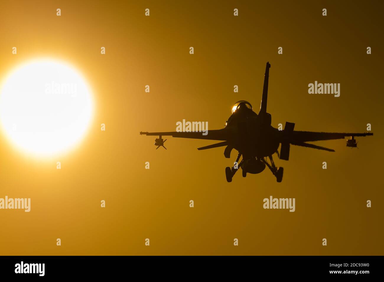 A F-16 Fighting Falcon multirole fighter jet is ready to land at sunset. Stock Photo