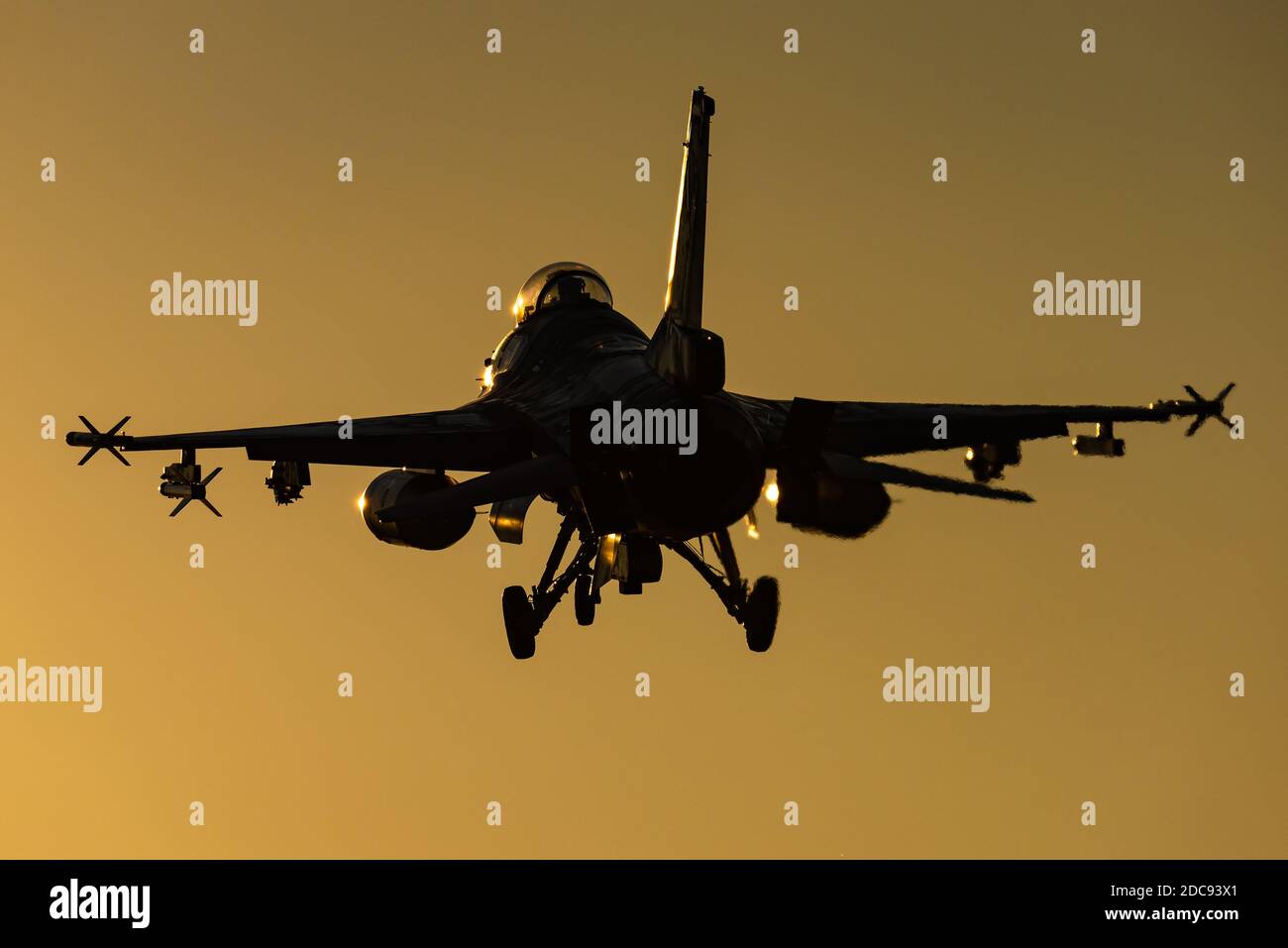 A F-16 Fighting Falcon multirole fighter jet is ready to land at sunset. Stock Photo