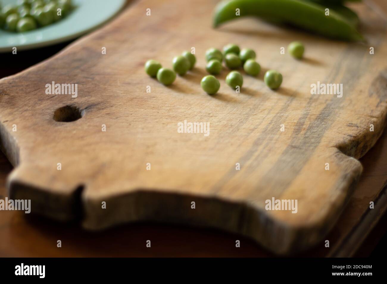 wooden cutting board shaped like a piggy with green peas on a wooden table Stock Photo