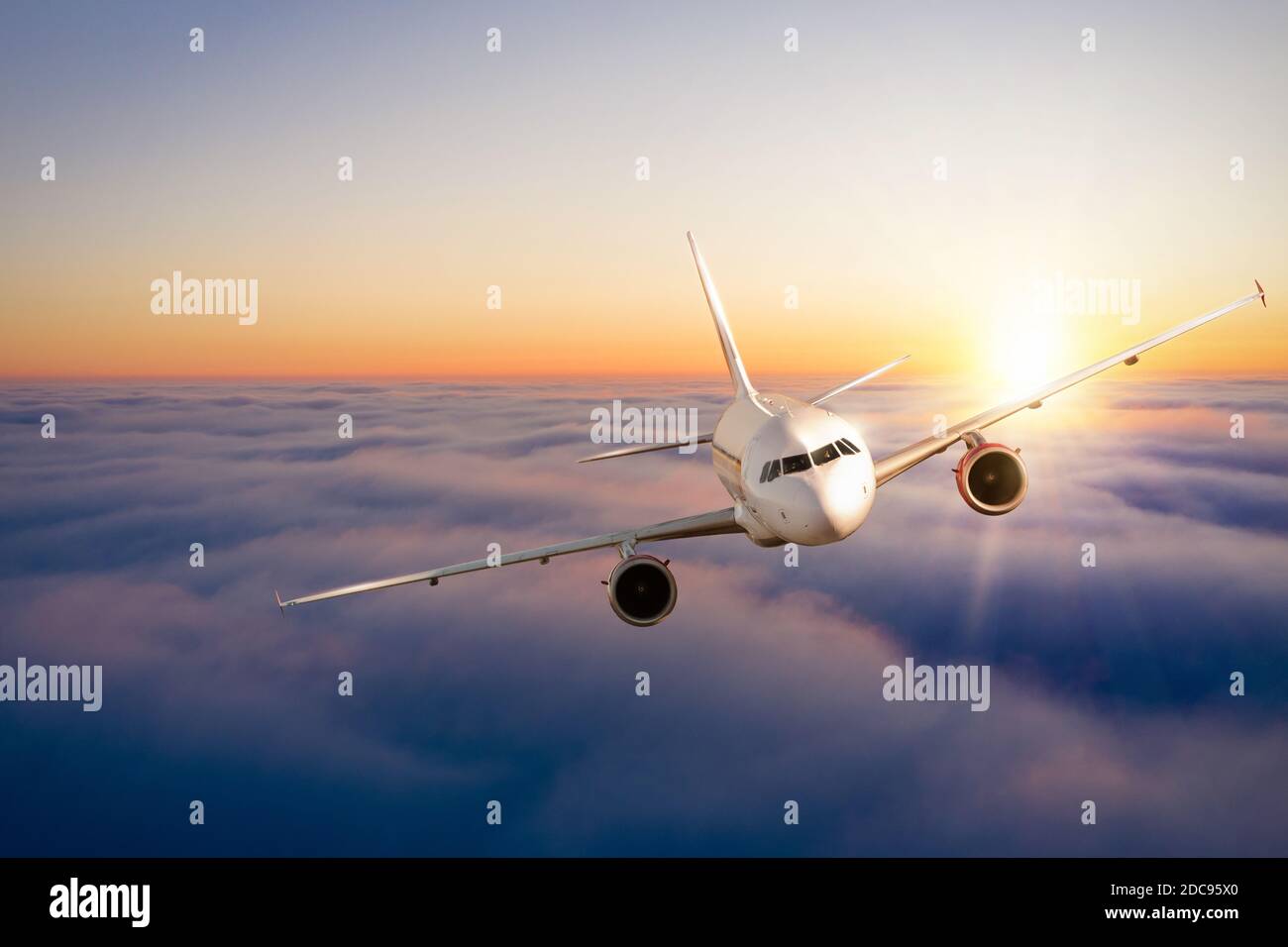 Commercial airplane flying above clouds in dramatic sunset light. Fast Travel and transportation concept Stock Photo