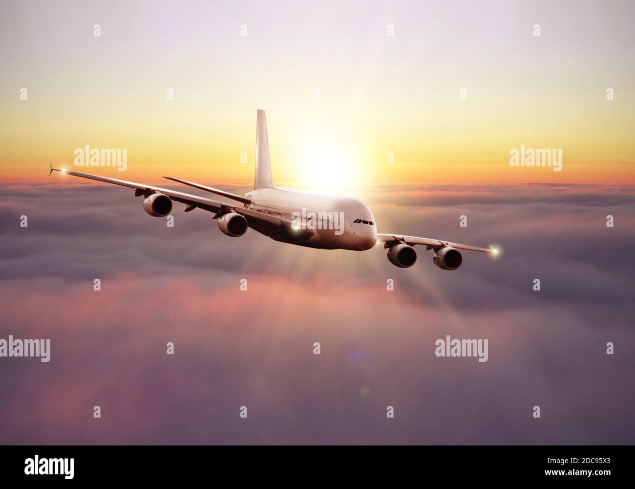 Commercial huge airplane flying above clouds in dramatic sunset light. Fast Travel and transportation concept Stock Photo