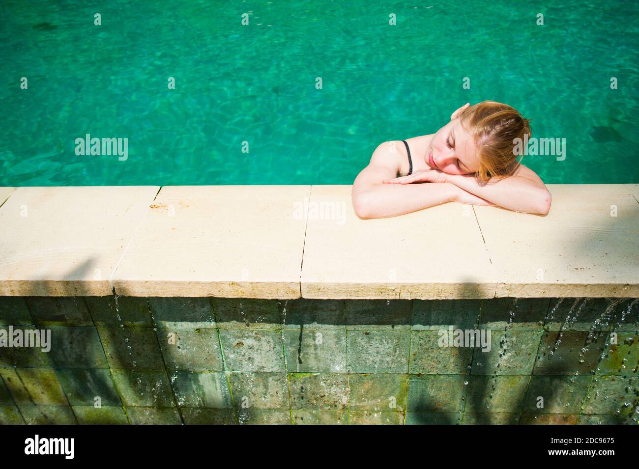 Tourist Relaxing in an Infinity Pool at Luxury Accommodation on Bali, Indonesia, Asia, background with copy space Stock Photo