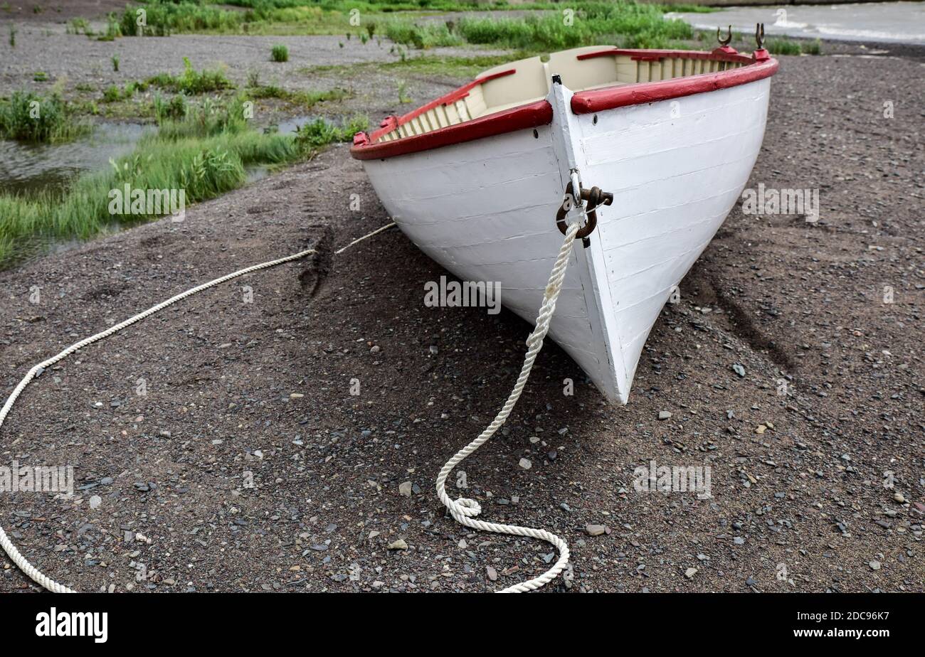 old vintage wooden rowboat beached along the sandy ocean shore Stock Photo