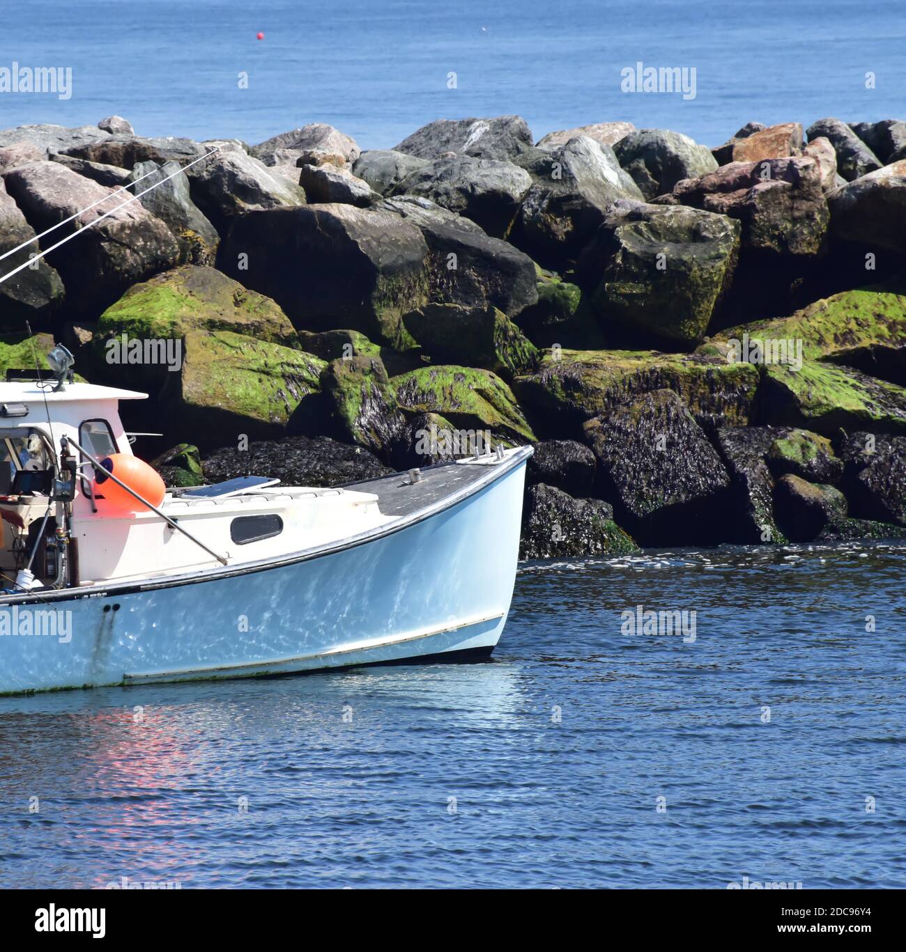 Fishing boat moving out to sea along the rocks Stock Photo - Alamy