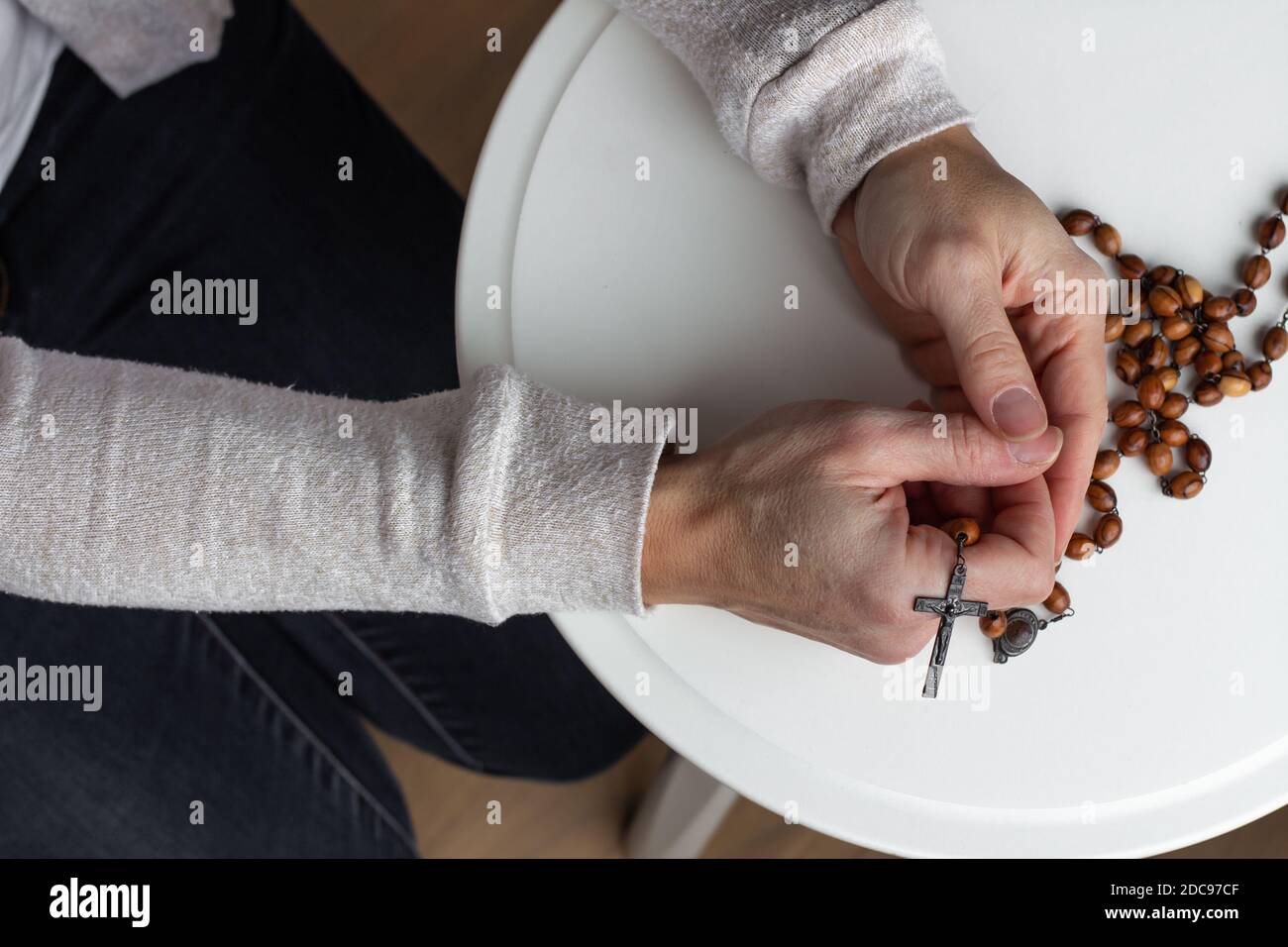 Woman's hands holding wood catholic rosary in prayer Stock Photo