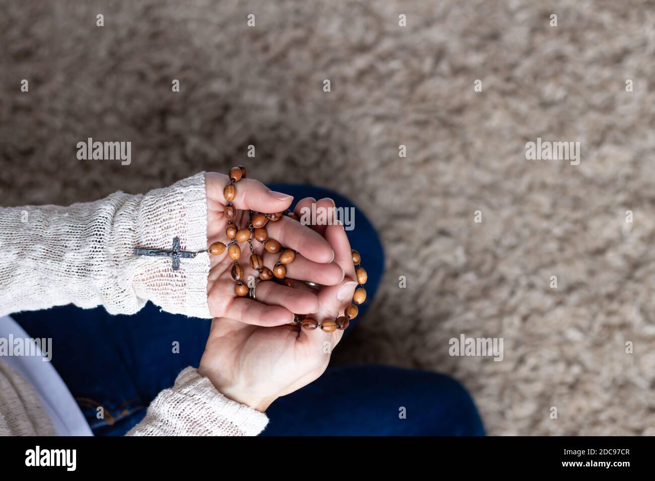 Woman's hands holding wood catholic rosary in prayer Stock Photo