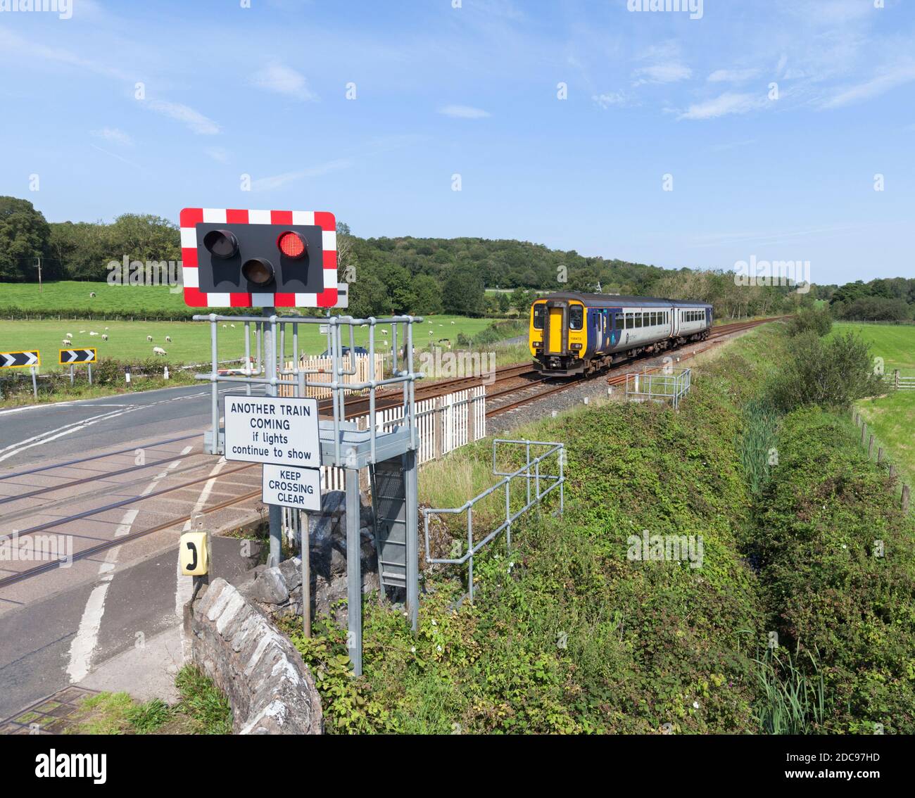 Silverdale automatic half barrier  ( AHB ) level crossing Lancashire with a Northern Rail class 156 train approaching Stock Photo