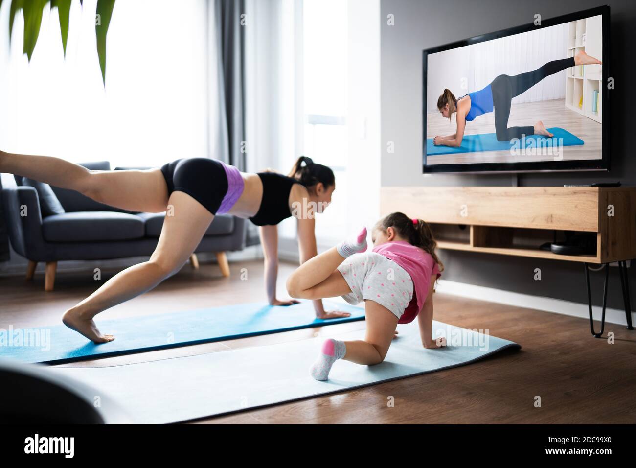 Woman And Her Child Girl Doing Online Fitness Exercise In Virtual Class Stock Photo
