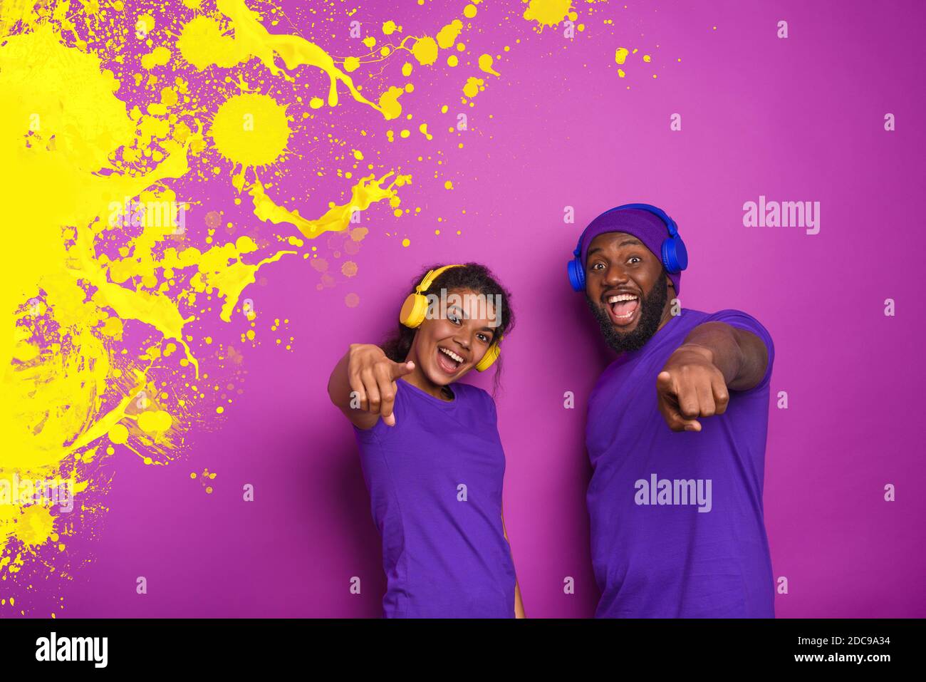 Couple with headset listen to music and have surprised expression. Purple background Stock Photo