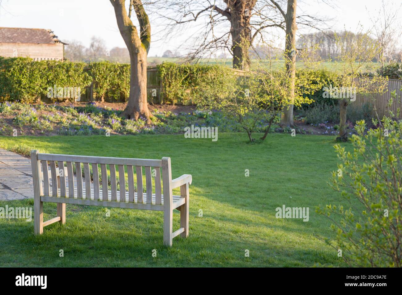 Large UK back garden in winter with a wooden garden bench on lawn, with a view of Buckinghamshire countryside Stock Photo