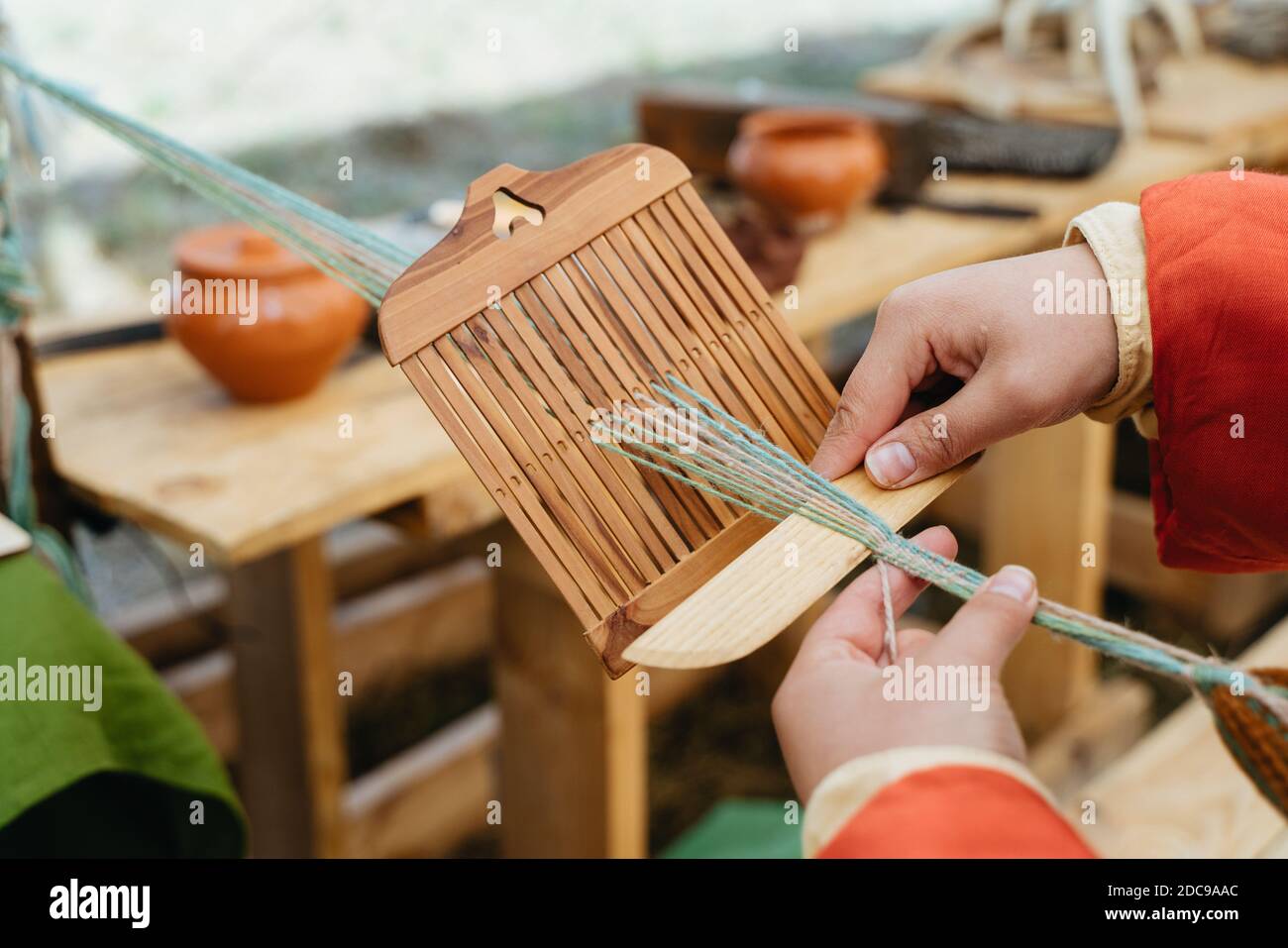Weaving craft. Woman in traditional dress works with hands Stock Photo