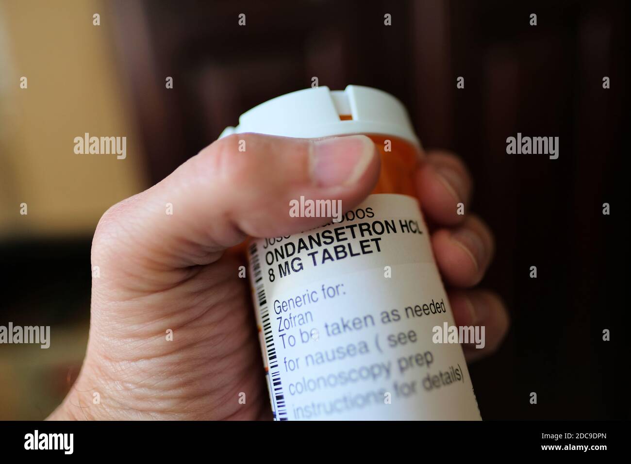 A man's hand holding an ondansetron pill bottle; used to prevent nausea and vomiting caused by surgery, cancer chemotherapy, radiation, colonoscopy. Stock Photo