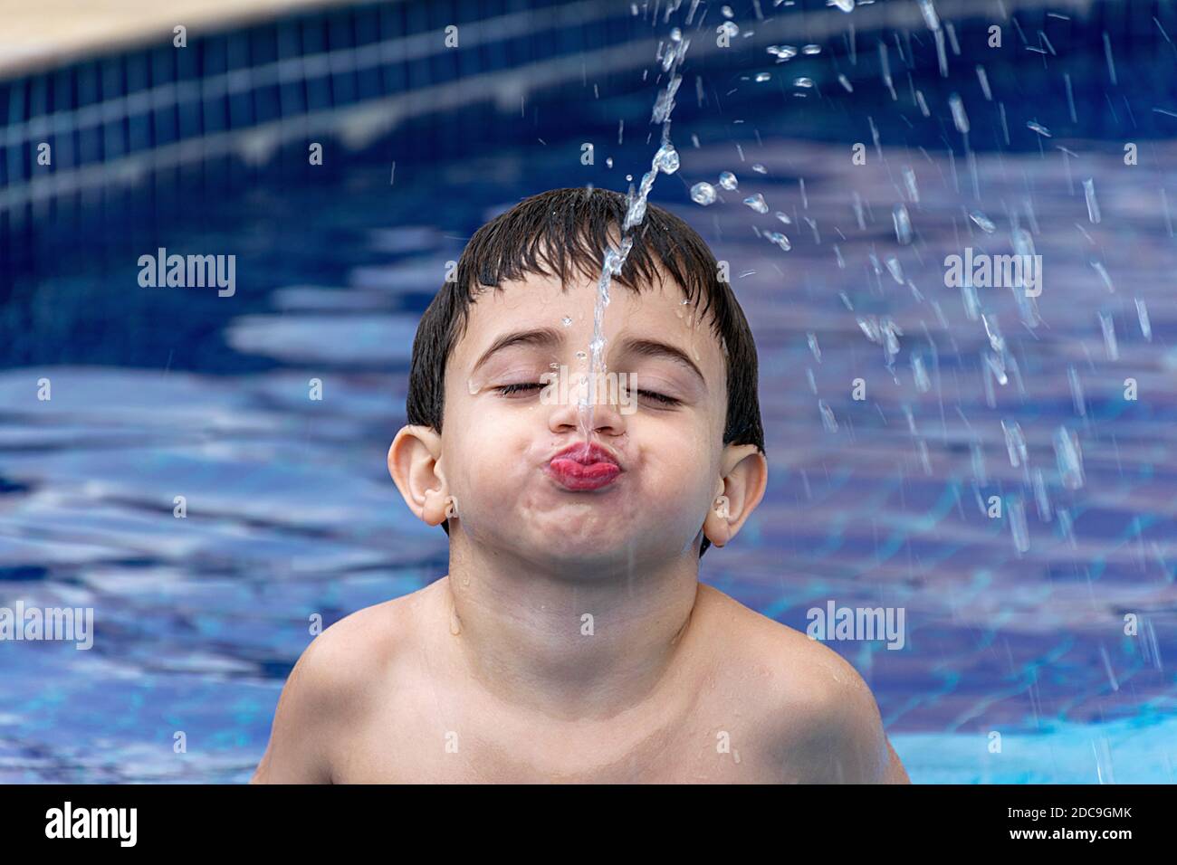 Close-up of a child squirting water by mouth. Stock Photo