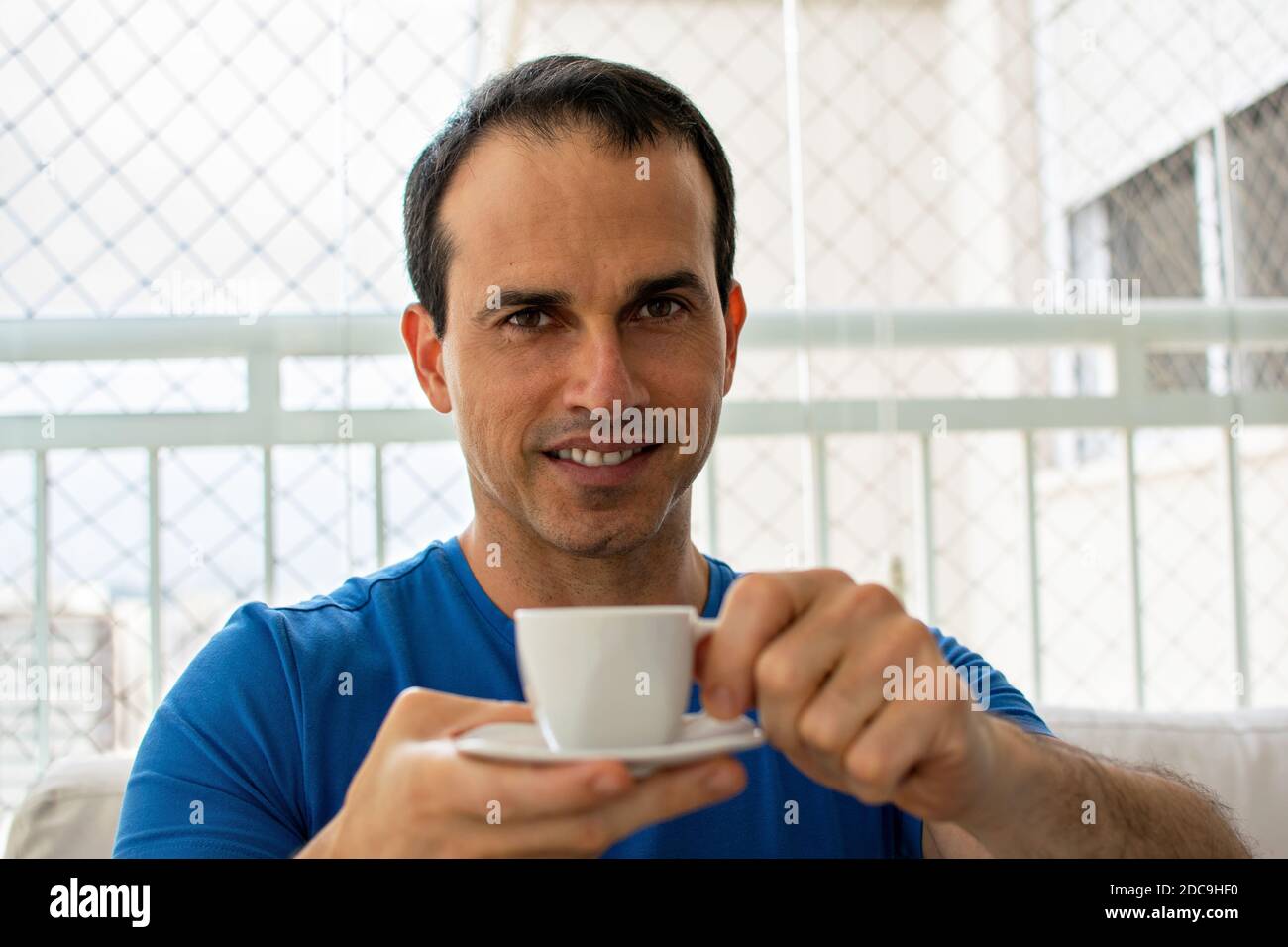 Smiling man offering a cup of coffee. Stock Photo