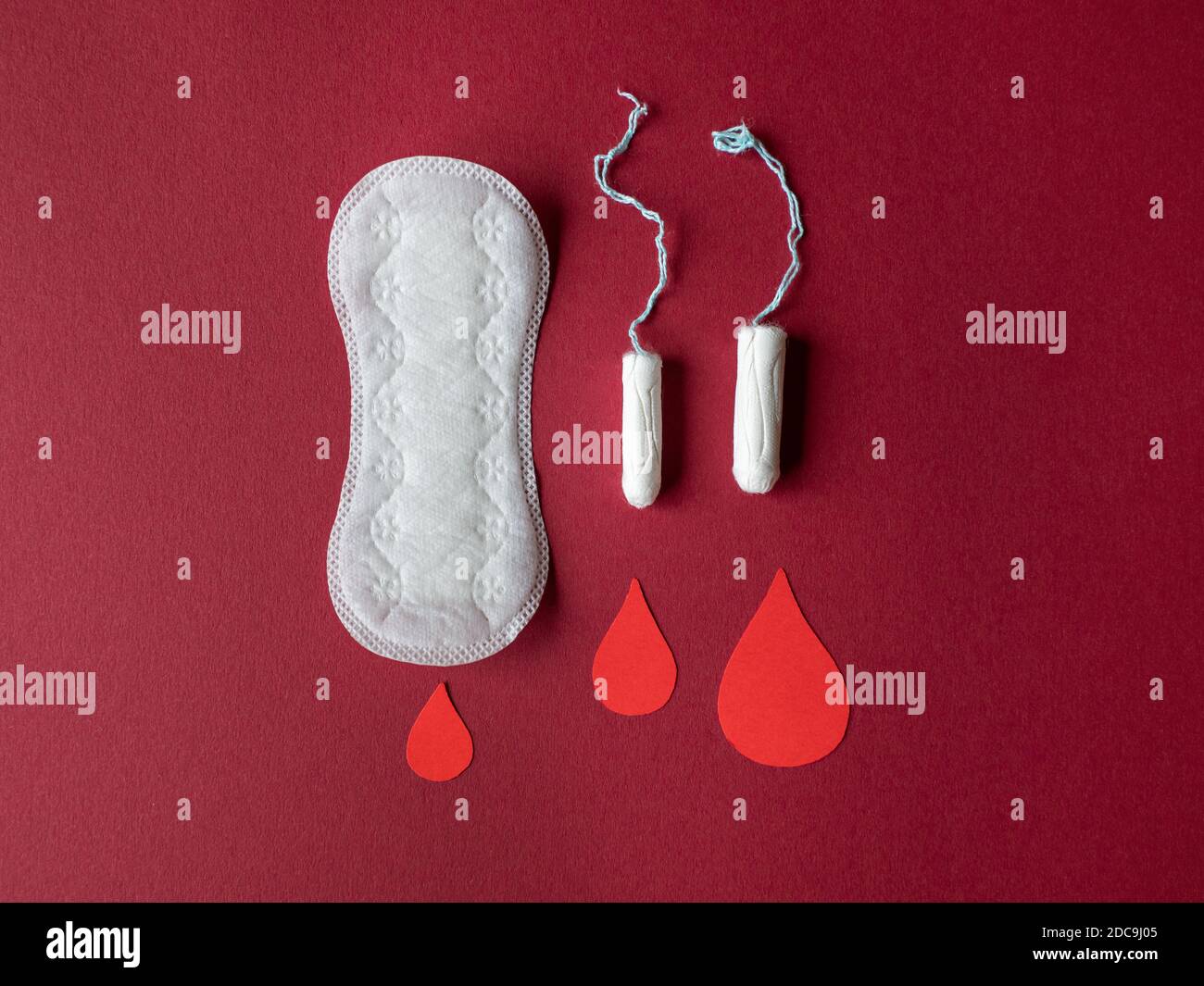 Female menstrual cycle / period products, a tampon and sanitary napkin isolated on red coloured background Stock Photo