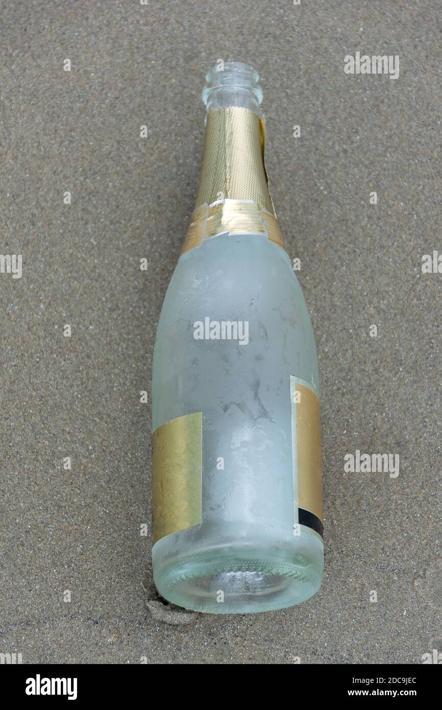 Empty sparkling bottle on the beach sand. Stock Photo