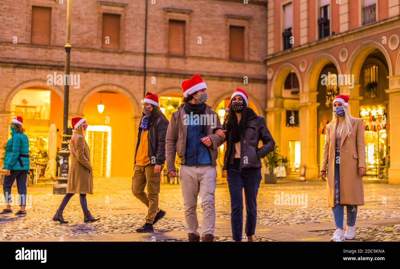 multiethnical crowd of people walking around the city centre street wearing christmas hat.group of friends celebrating festivities in a serious way Stock Photo