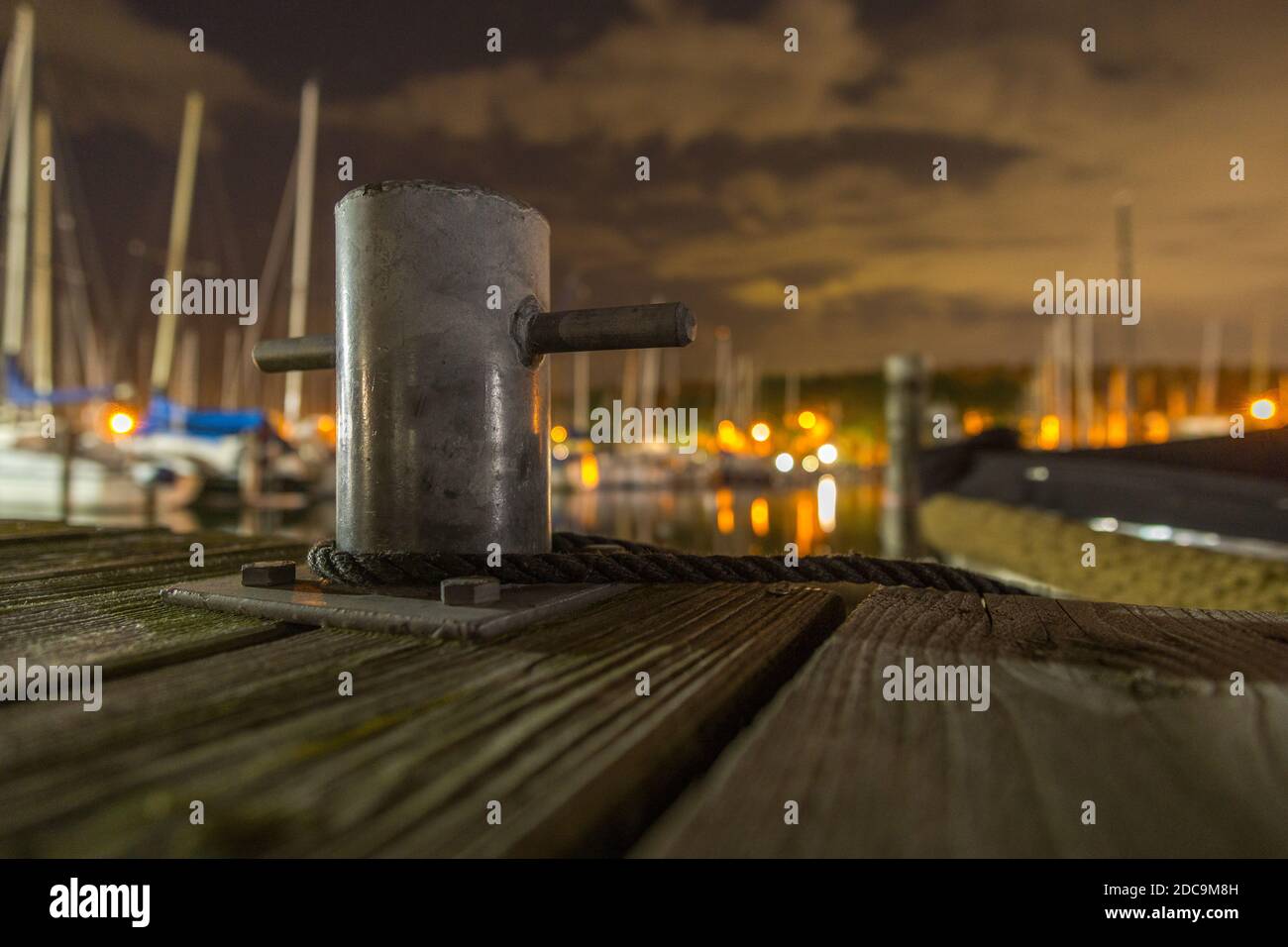 Bollard on wooden pier with rope at night Stock Photo