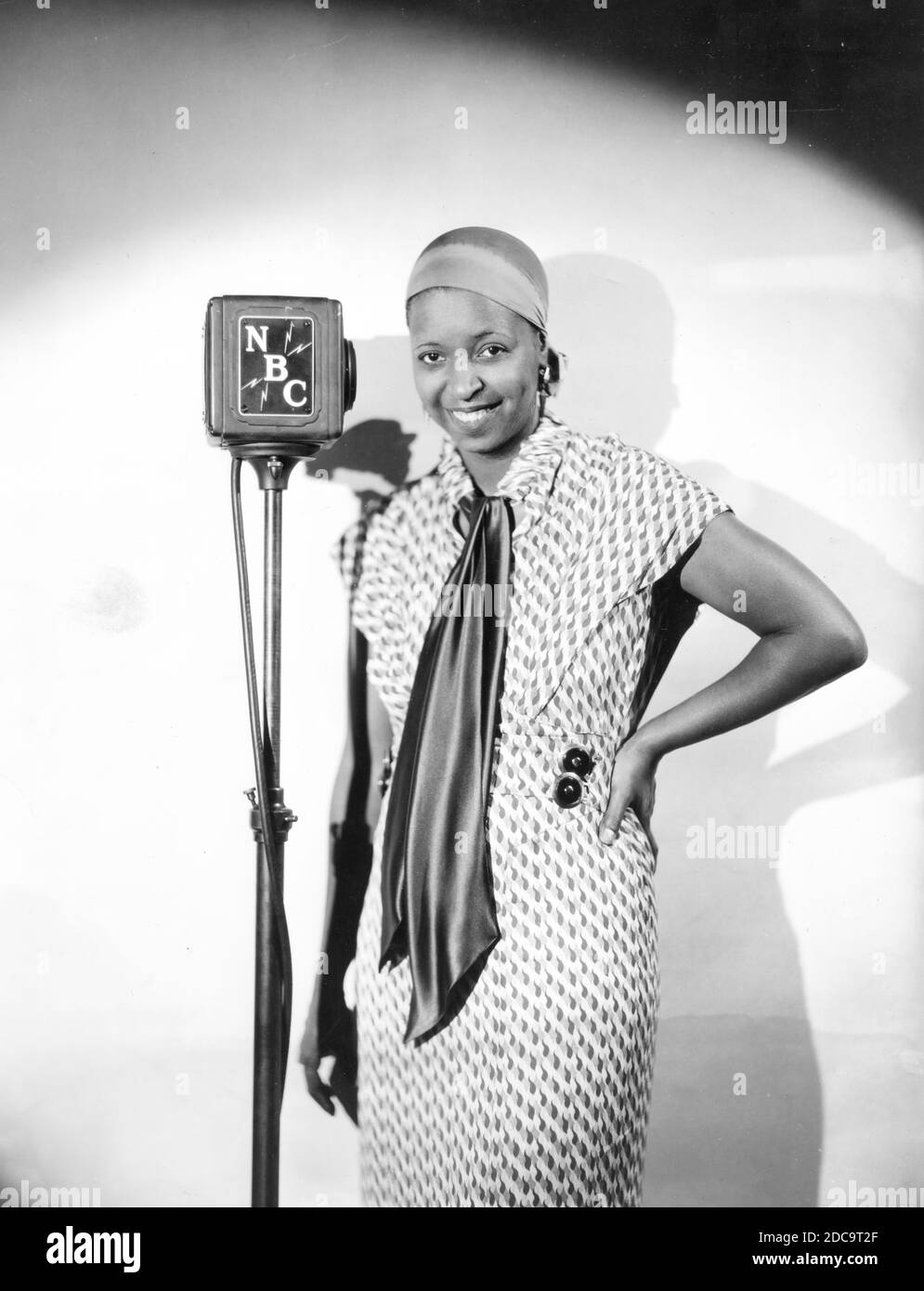 American Blues singer Ethel Waters (1896-1977) poses with an NBC Radio microphone in 1933. Ms. Waters also sang jazz, pop, and swing. She was a very successful actress and was nominated for an Academy Award and a Primetime Emmy Award. The 1933 caption found with this photo says, 'From laundress to the sensational singer of the day for her blues. She is the person who introduced 'Stormy Weather' and made it what it is today. She uses it as her theme song on her broadcasts over the NBC-WJZ network.'    To see my other related images, Search:  Prestor  vintage  music  African Stock Photo