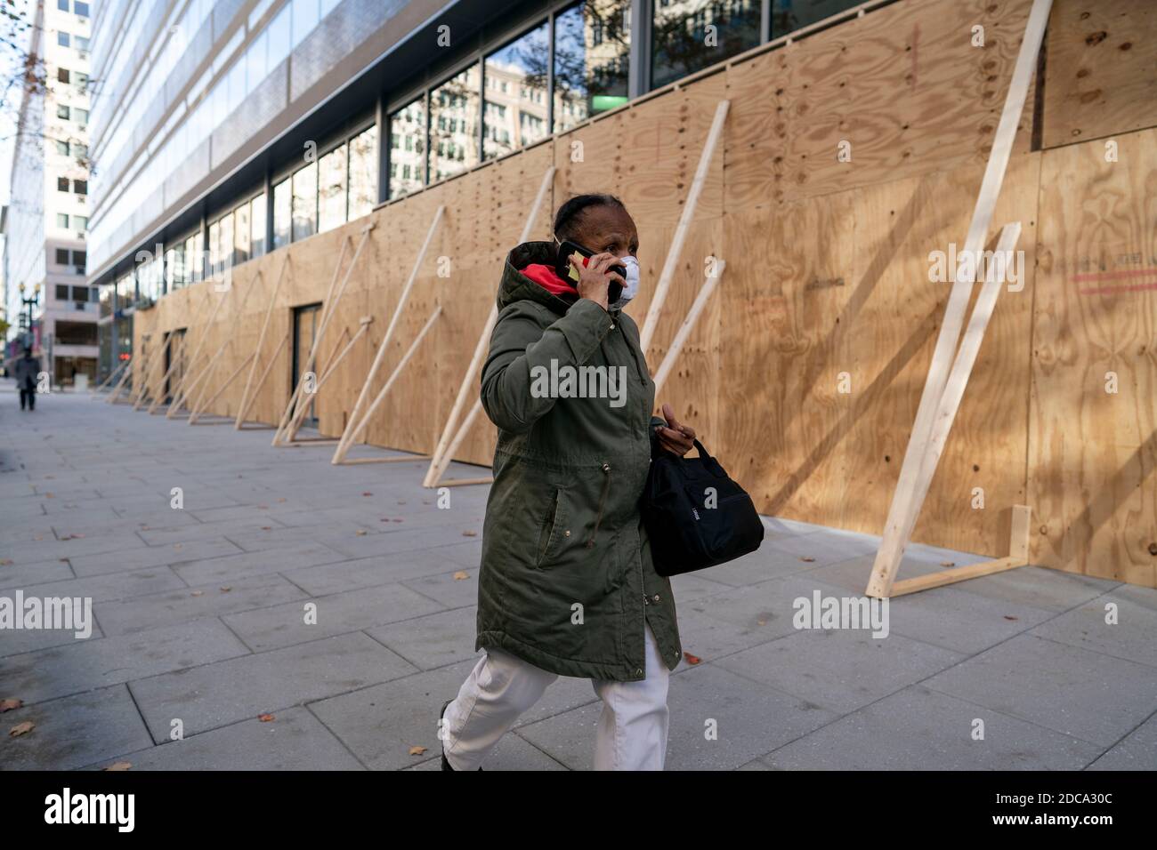 Washington, USA. 20th Nov, 2020. A man walks past an office building boarded up with plywood in Washington, DC, the United States, on Nov. 19, 2020. The number of initial jobless claims in the United States rose to 742,000 last week, as the labor market recovery slows amid surging COVID-19 cases, the Labor Department reported on Thursday. Credit: Liu Jie/Xinhua/Alamy Live News Stock Photo