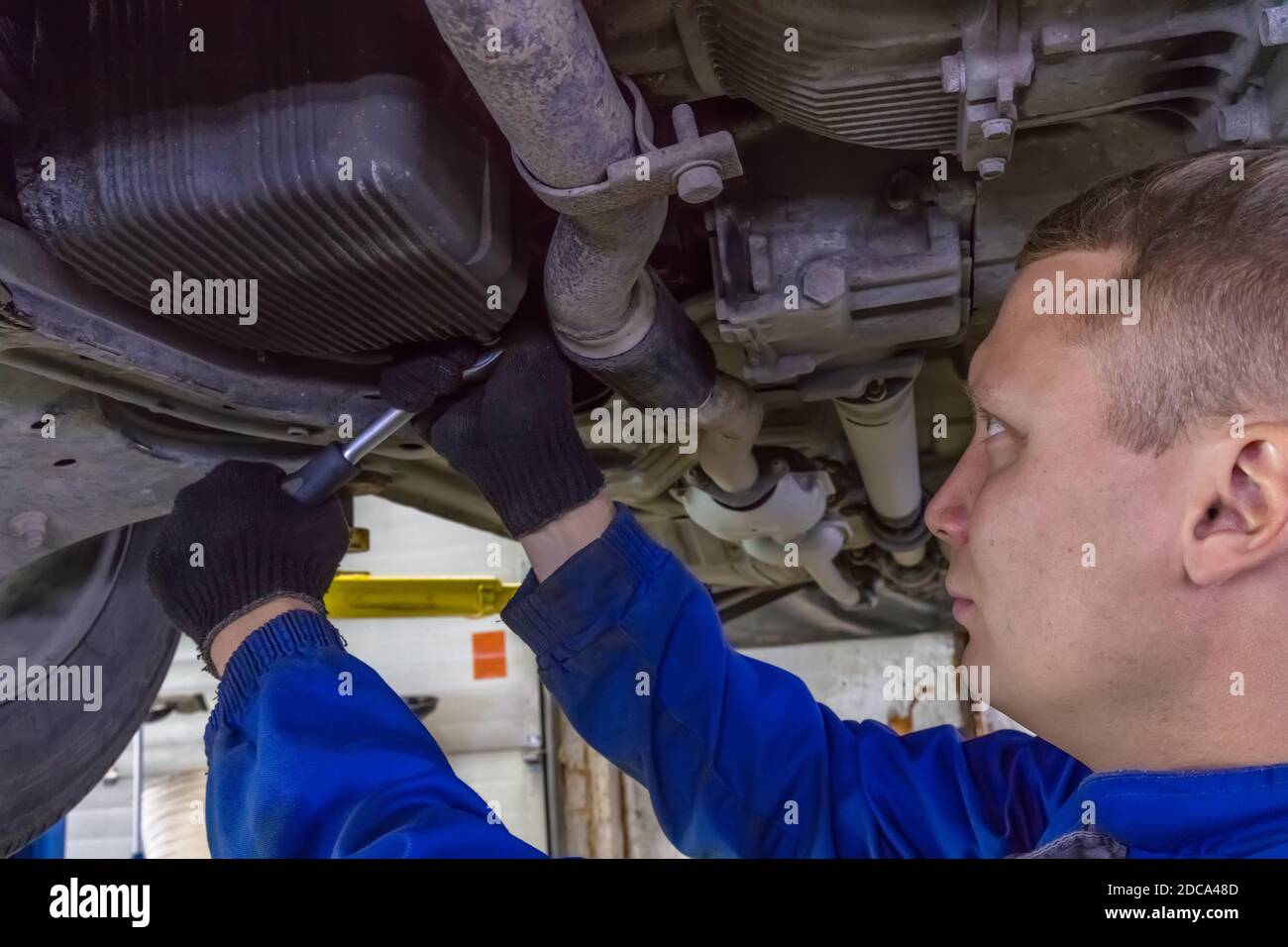 A closeup shot of a mechanic working under a car at the garage