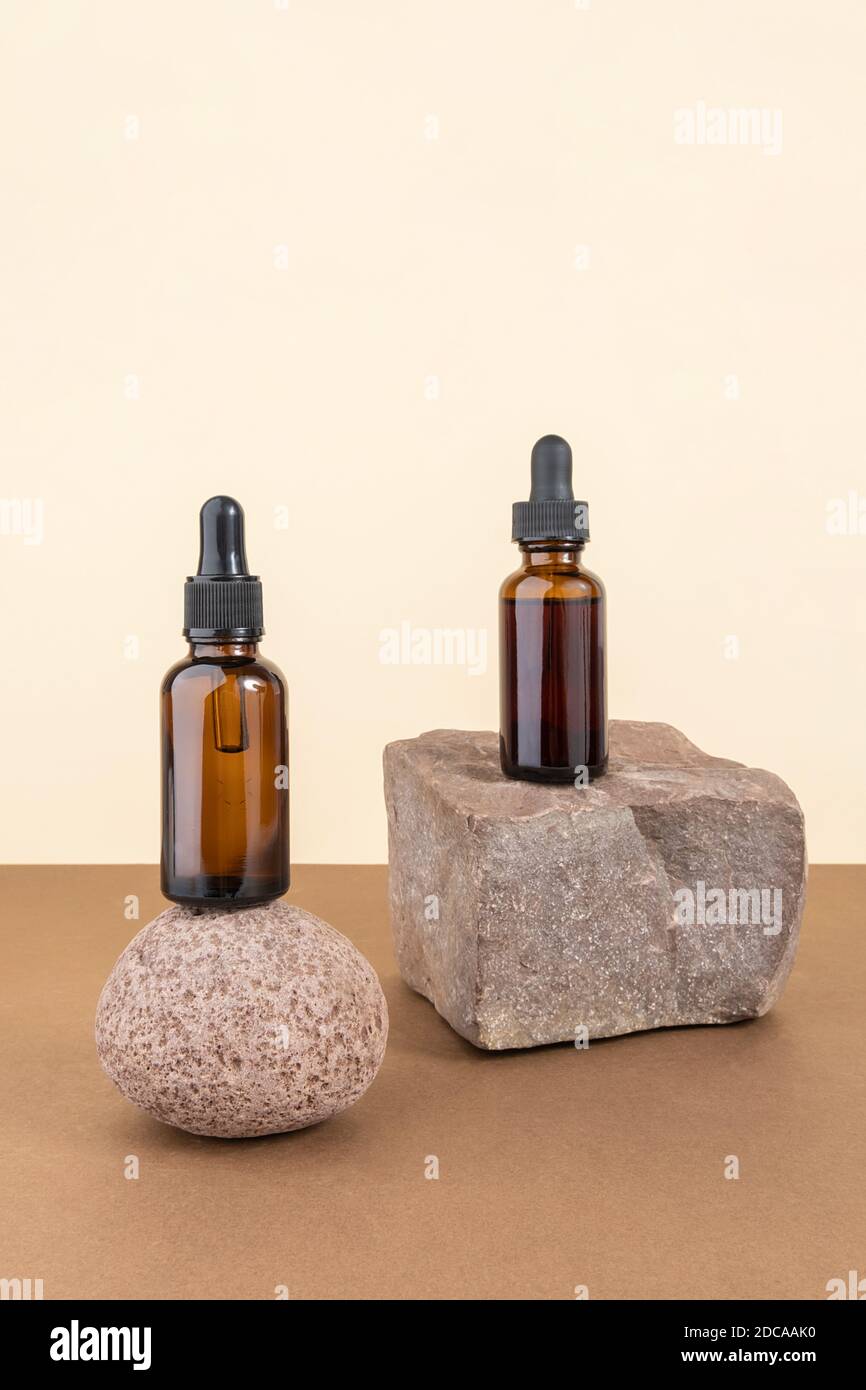 Two cosmetic brown glass bottles with pipette on stones, beige brown background. Natural Organic Spa Cosmetic concept. Front view Copy space Stock Photo