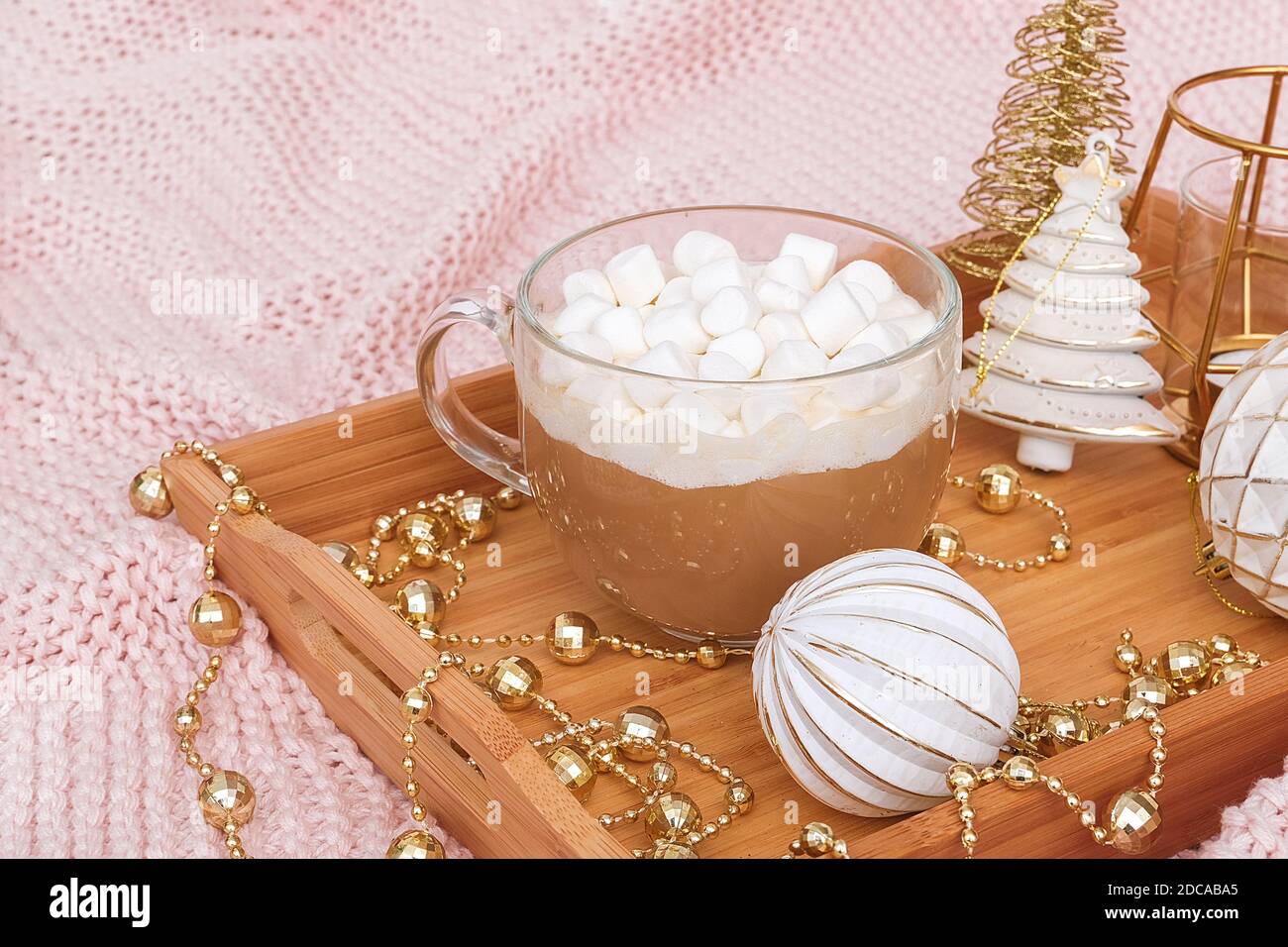 Wooden tray with cup of cocoa, marshmallows and christmas decorations on warm knitted pink plaid. Xmas or New year good morning concept. Stock Photo