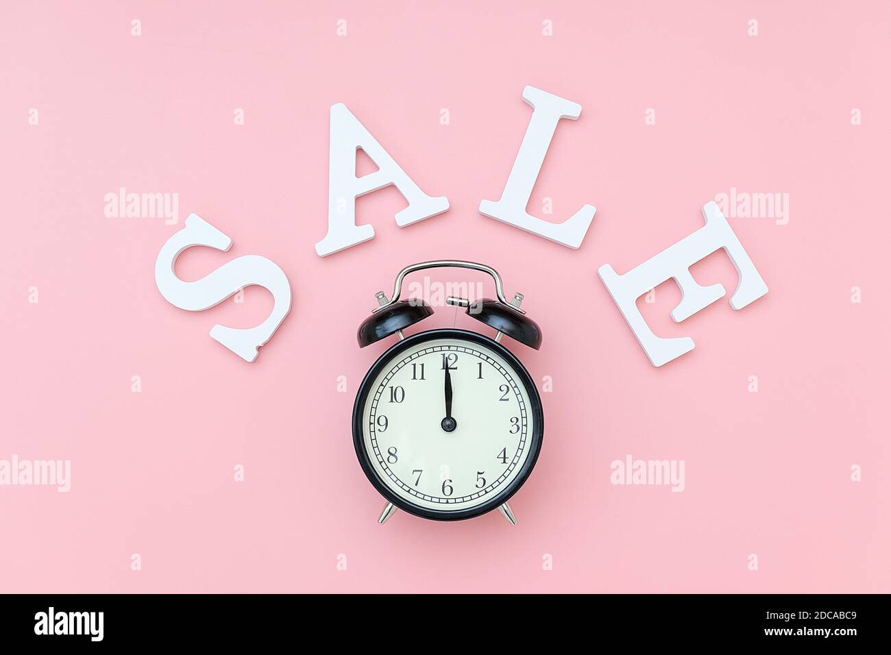 Black alarm clock in craft package on a pink background. Concept Black friday , season sales