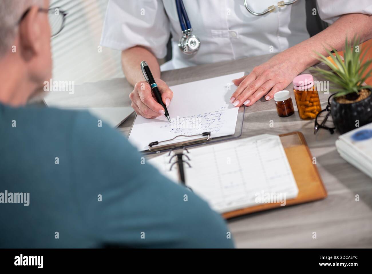 Female doctor writing prescription to her patient in medical office ...