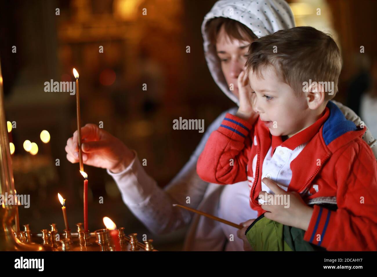 Mother and son put candles in the Russian Orthodox Church Stock Photo