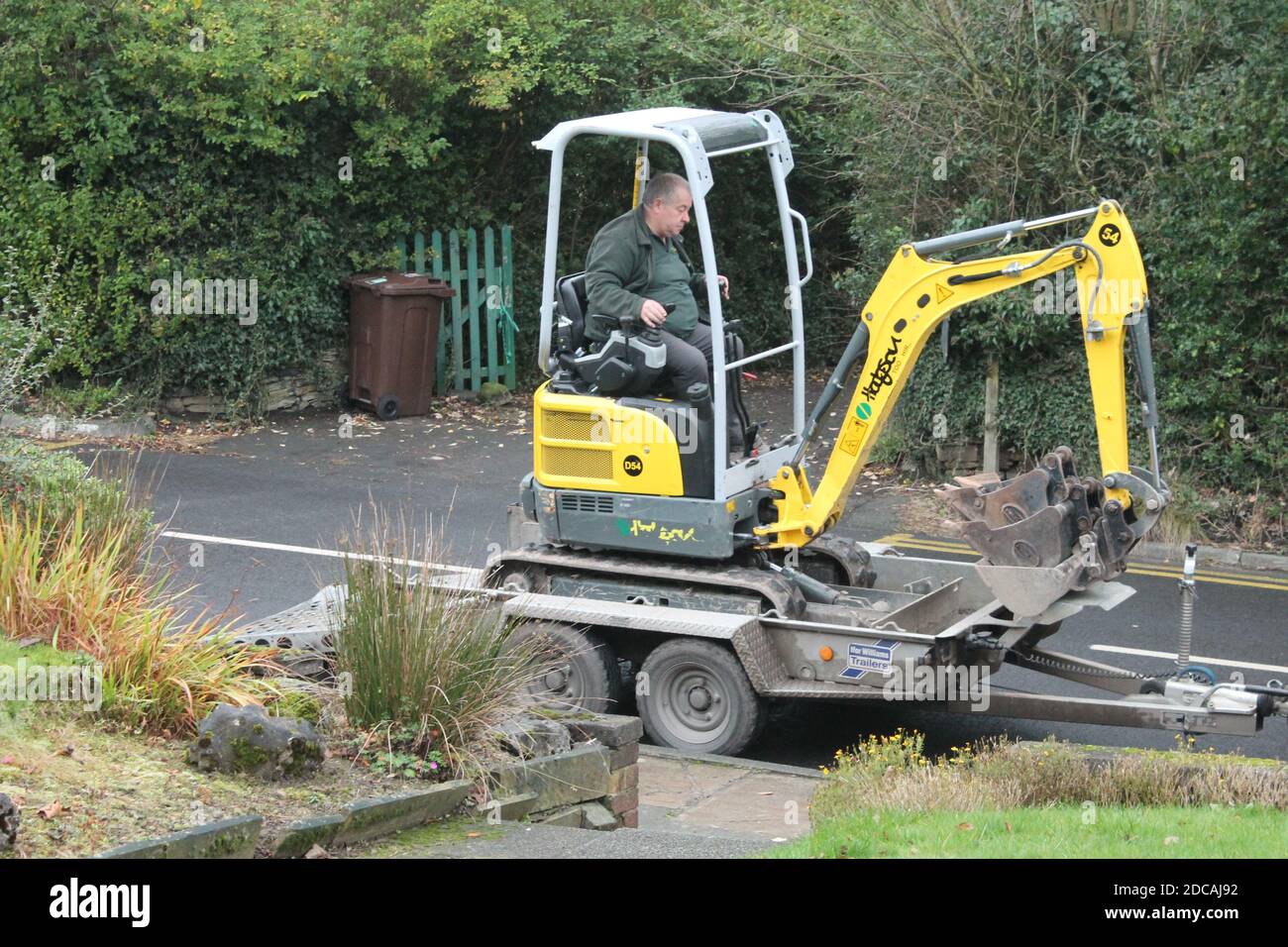 Mature man on driving a mini digger onto the back of a trailer Stock Photo