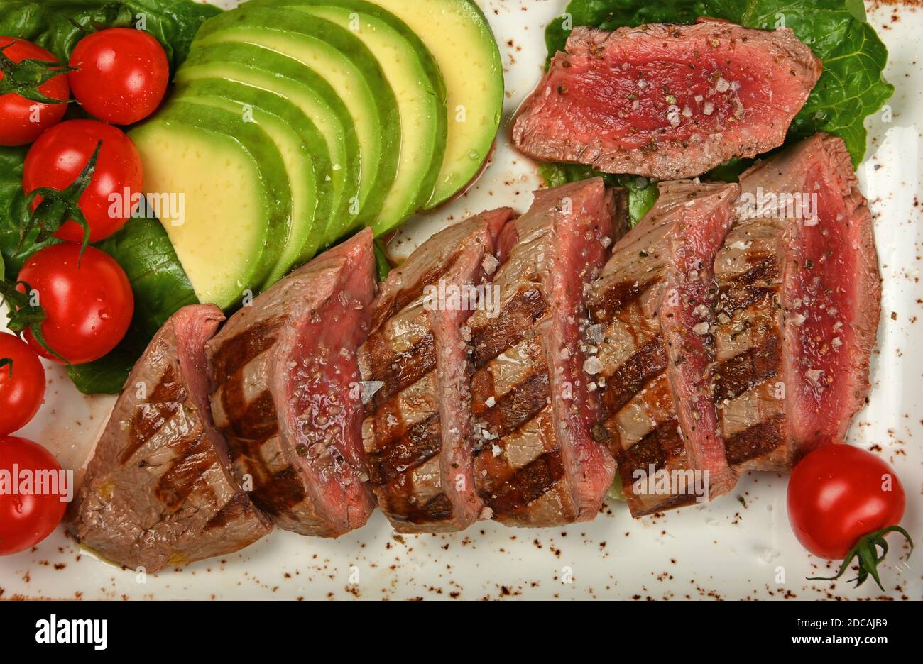 Close up grilled beef tenderloin steak sliced to serve with vegetables