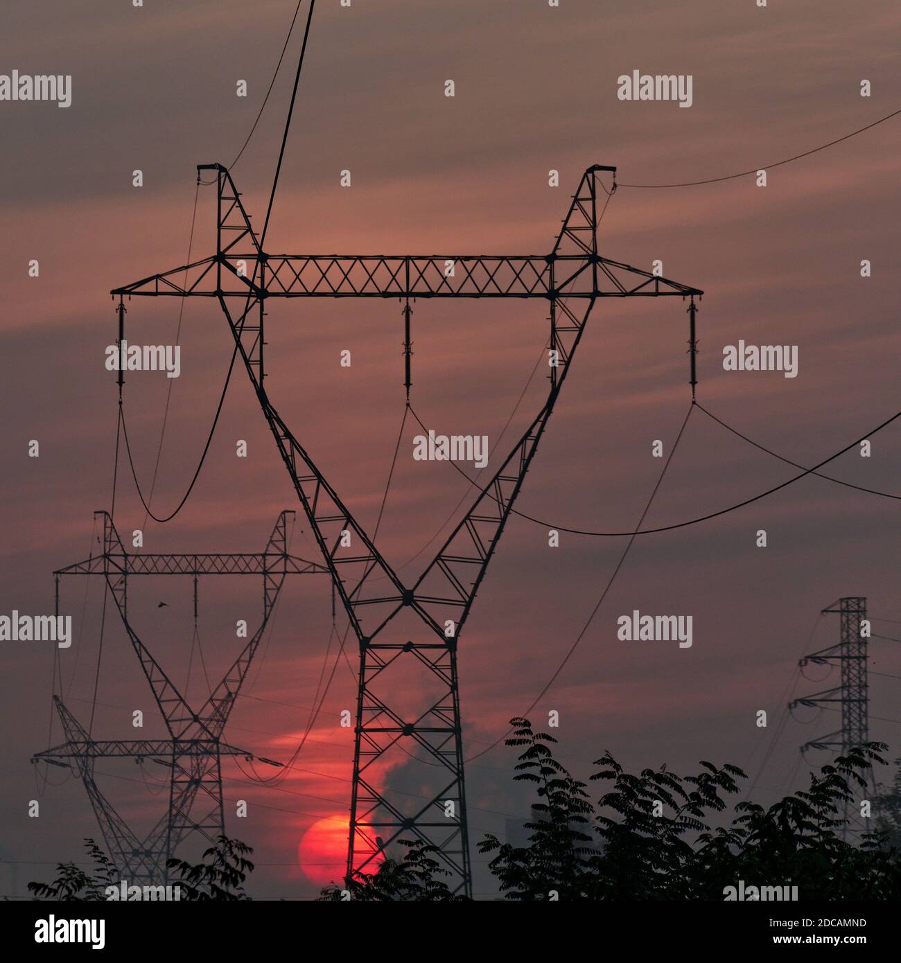 Electricity pylons and power lines at sunrise/sunset Stock Photo - Alamy
