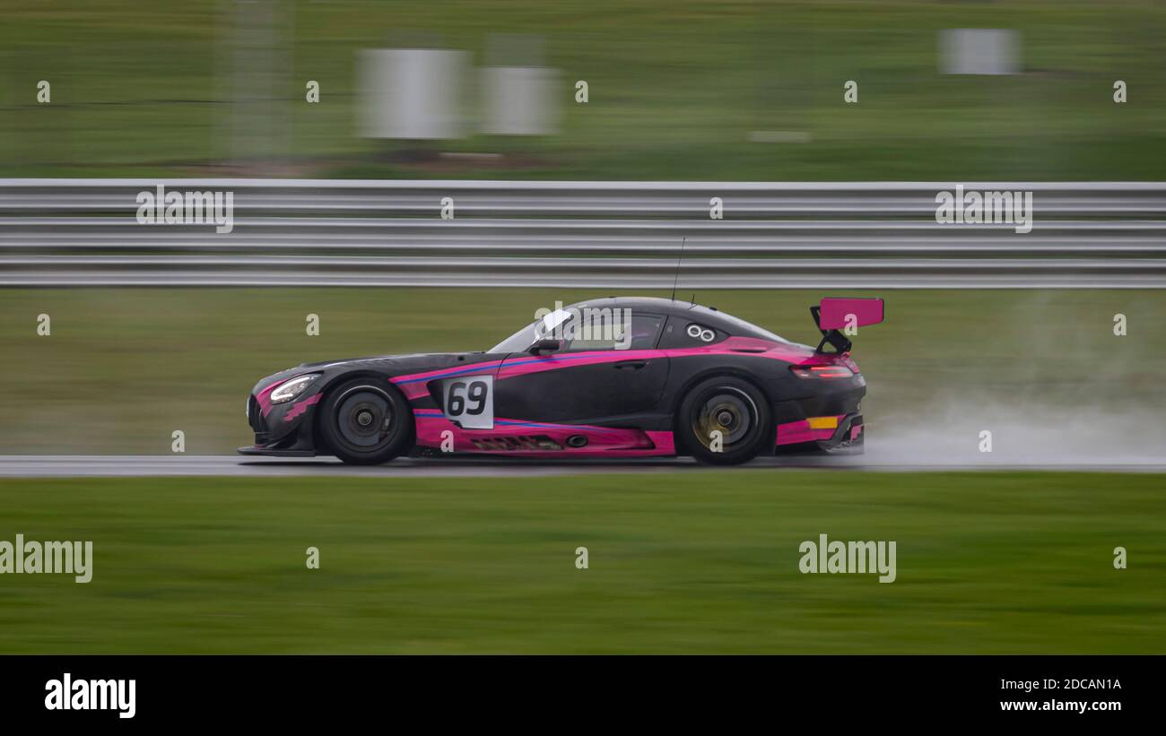 A panning shot of a racing car as it circuits a track. Stock Photo