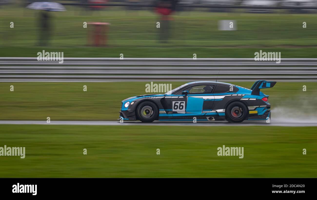 A panning shot of a racing car as it circuits a track. Stock Photo