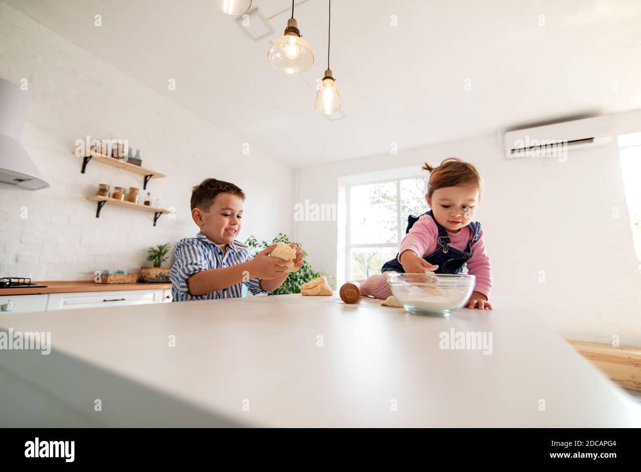 Children knead the dough sitting on the kitchen table Stock Photo - Alamy