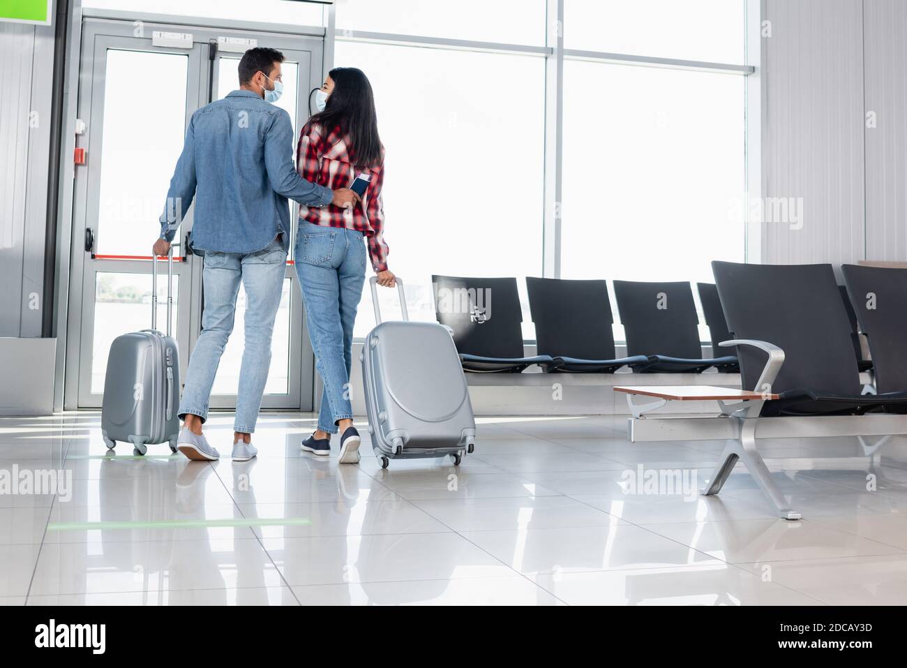 back view of multicultural couple walking with luggage in airport Stock ...