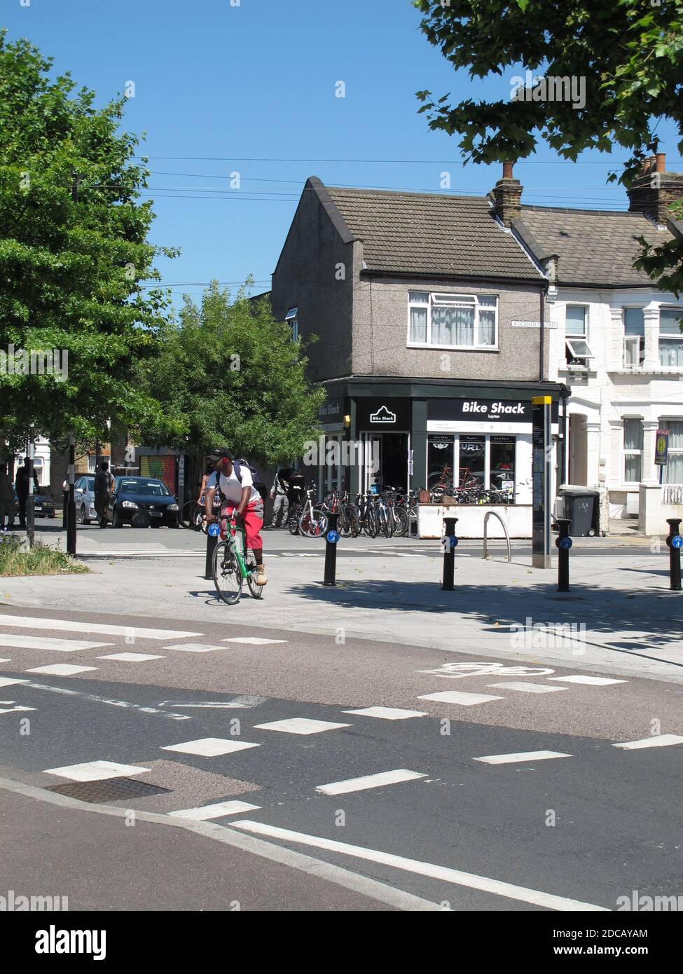 London, UK. A cyclist approaches a crossing on Ruckholt Road. Part of Waltham Forest's Mini-Holland scheme for safer streets. Bike shop in background. Stock Photo