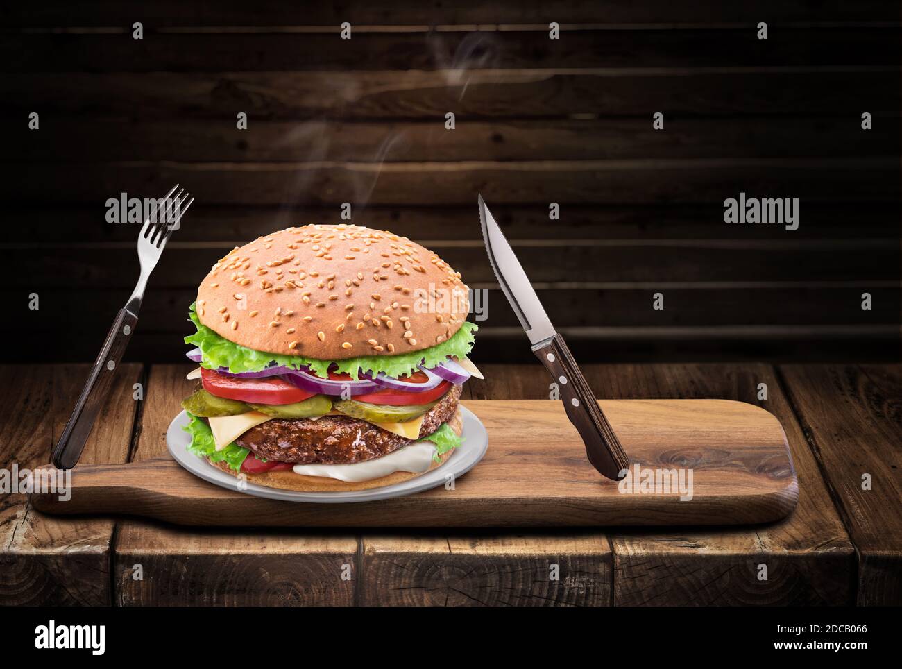 Conceptual photo of typical desired tasty hot homemade burger or cheeseburger on wood table. Knife and fork waiting for dinner. Stock Photo