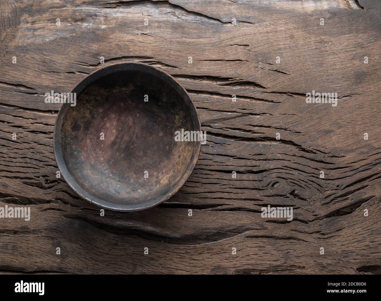 Empty old wooden plate on cracked old wooden table. Top view. Stock Photo