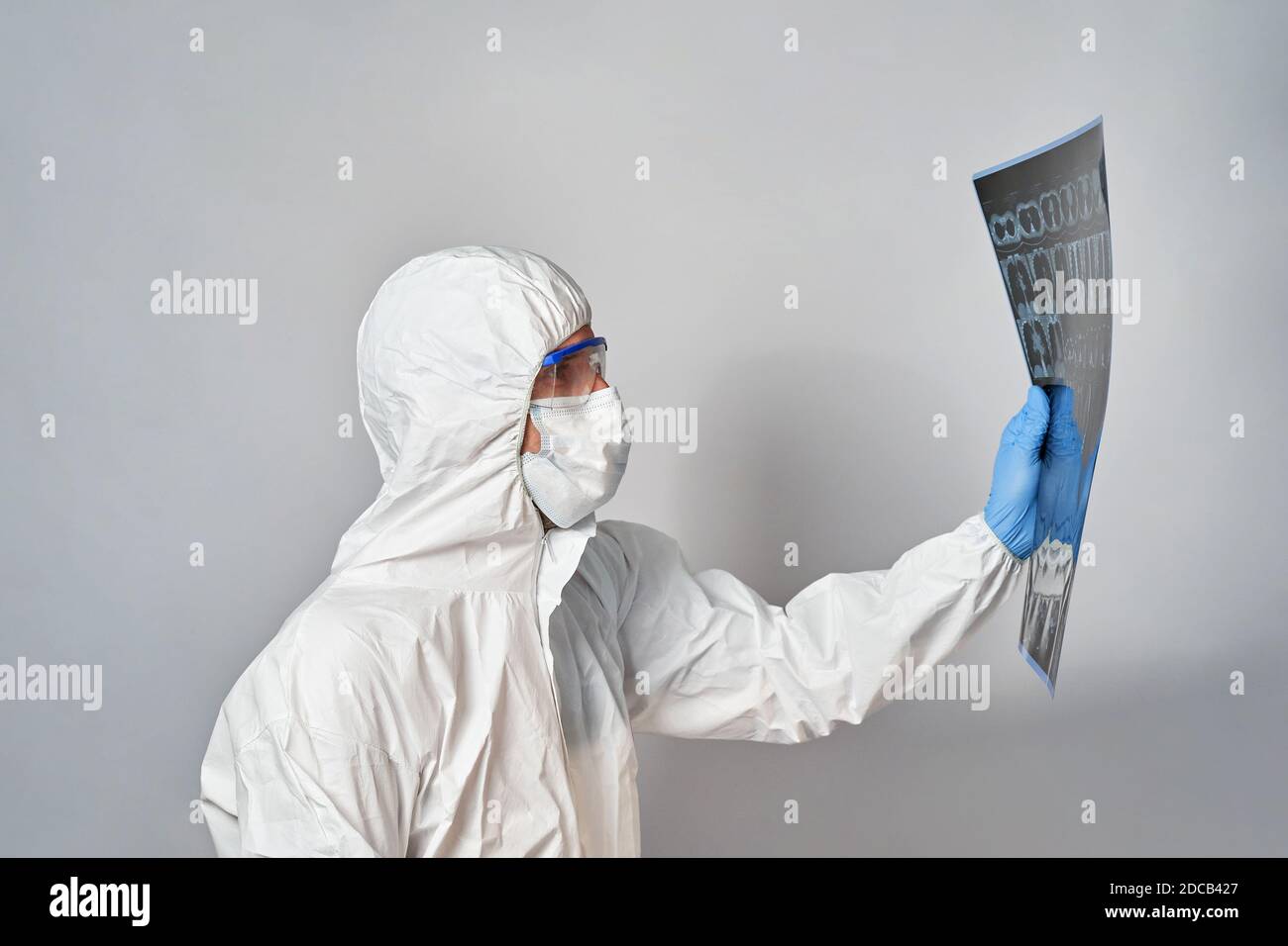 a doctor in a protective suit and mask looks at the results of a CT scan of the lungs Stock Photo