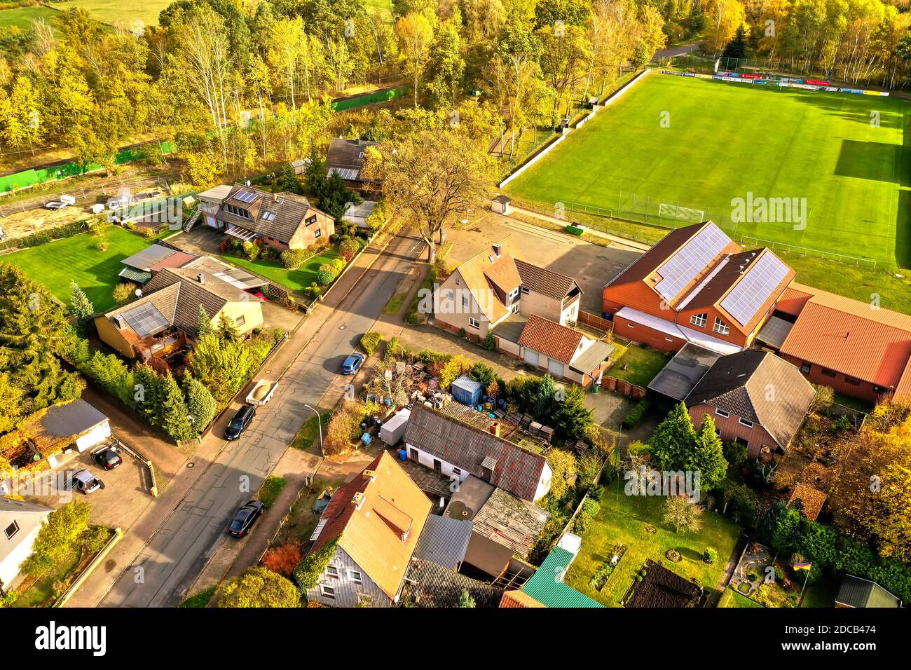 Aerial view of the edge of a village with private homes and a sports