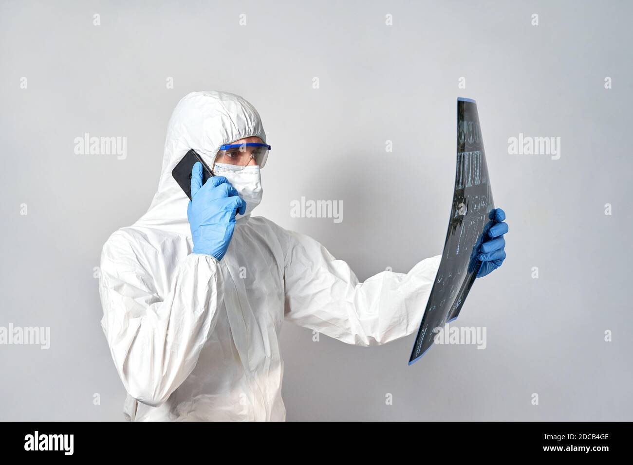a doctor in a protective suit and mask looks at the results of a CT scan .coronavirus. Stock Photo